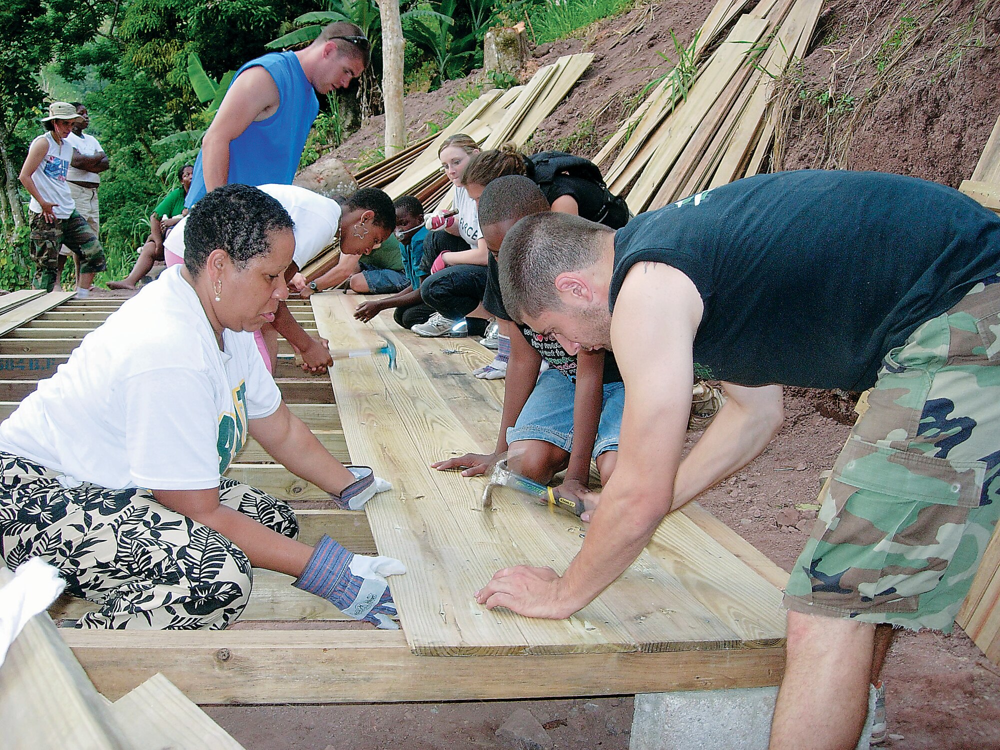 CASCADE, Jamaica — Master Sgt. Cynthia Jones, left, a reservist from the 445th Maintenance Squadron, grips the board as Senior Airman Ryan Kocak, of 88th Diagnostics and Therapeutics Squadron, wields the hammer on a piece of wood for the flooring in the tongue-and-groove, 12 by 20 foot home they helped construct July 10. From July 7-14, 14 active duty and Reserve Airmen from Wright-Patterson AFB took leave time in order to live among the Jamaican people and build a home for a single woman and her two daughters who were in need. (Courtesy photo)