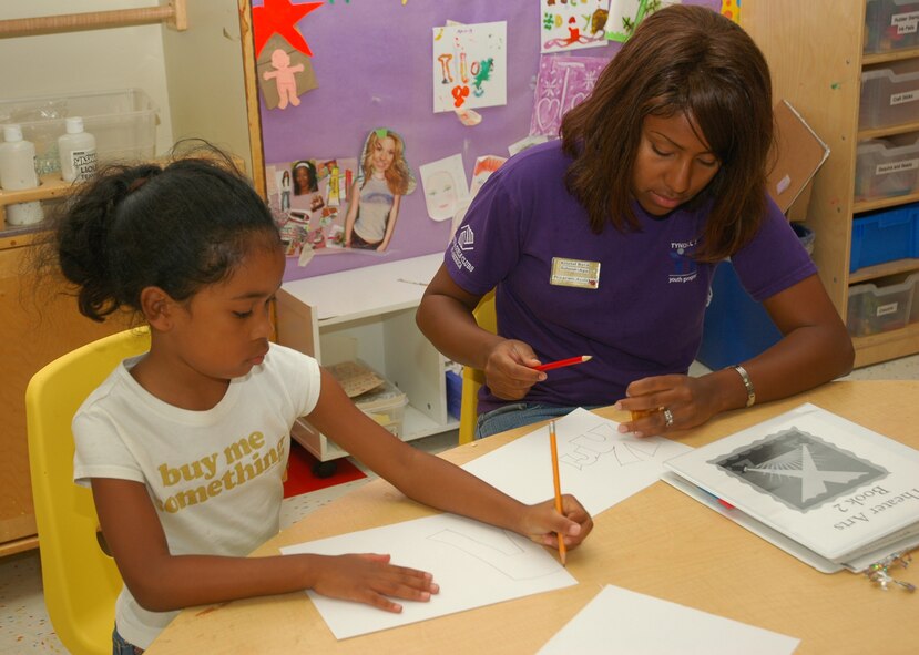 Barbara Bard, Tyndall Elementary School second-grade student, draws with help from Kristel Byrd, Youth Center program assistant. (U.S. Air Force photo by Staff Sgt. Vesta Anderson)