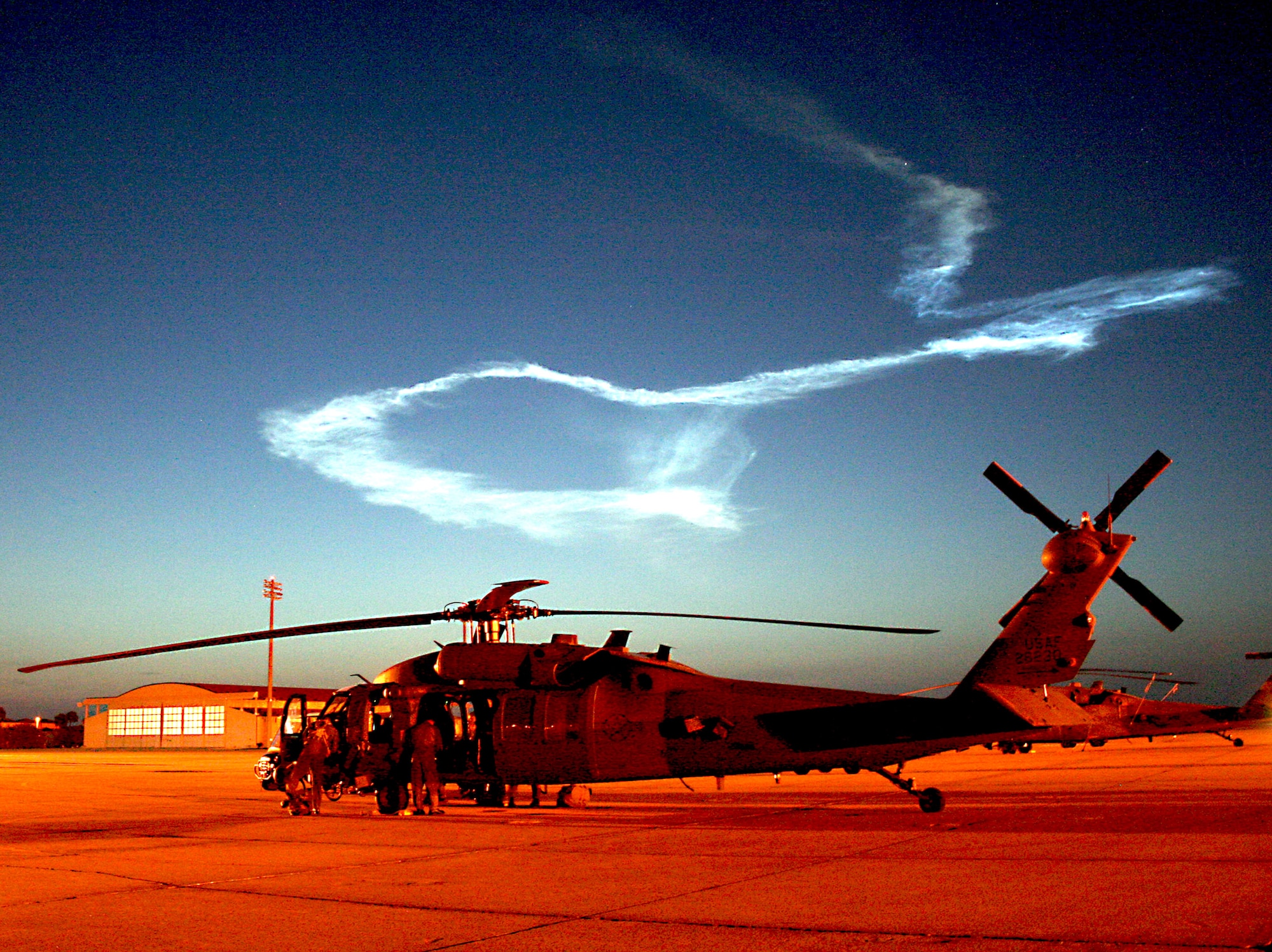 The crew of a 920th Rescue Wing HH-60G Pave Hawk helicopter conducts post-flight operations after supporting a NASA Delta II rocket launch from Kennedy Space Center just before 5:30 a.m. Aug. 4 at Patrick Air Force Base, Fla. Reservists from the 920th RQW are responsible for clearing the Eastern range before all space shuttle and rocket launches to ensure no boats are in the launch path. The lazy twist of smoke in the early-morning sky is all that remains from the trail left by the rocket, which carried the Phoenix spacecraft on the first leg of its trip to Mars' arctic plain. (U.S. Air Force photo/Staff Sgt. Paul Flipse)
