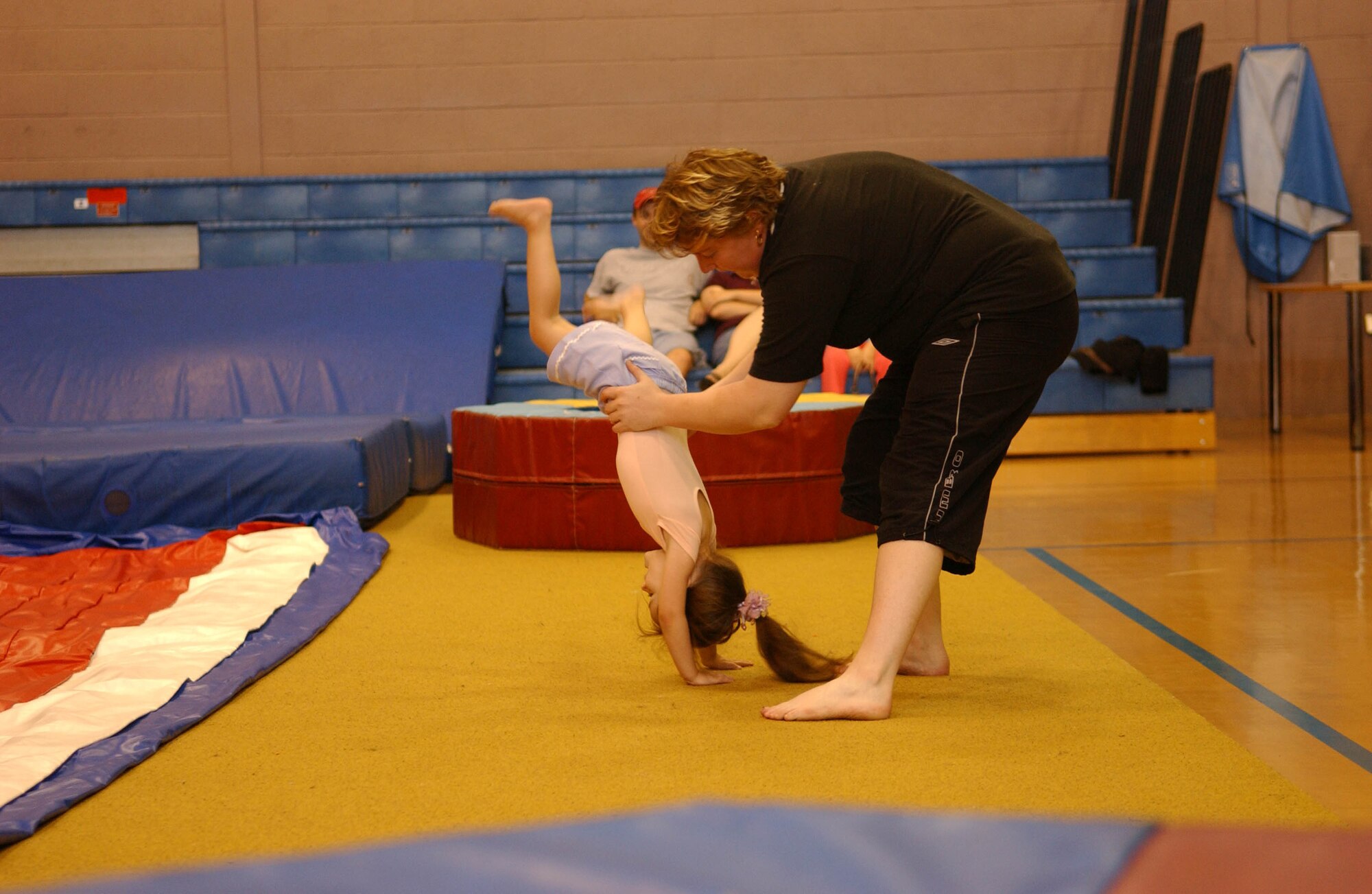 Averi Martin performs a handstand with a little help from gymnastics instructor, Josie Wilkes. (U.S. Air Force photo be Joe Strouth)