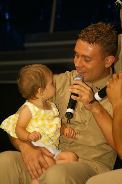 Senior Airman Nicholas Amari, 122nd Security Forces Squadron, Fort Wayne IAP (ANG), IN., and Tops in Blue performer, sings "Daddy's Girl" to Norah Brock, 11 months, daughter of Tops in Blue technician, Senior Matthew Brock, 420th Logistics Readiness Squadron, RAF Fairford. The concert was held in Hangar 814 July 25. (U.S. Air Force photo by Karen Abeyasekere)