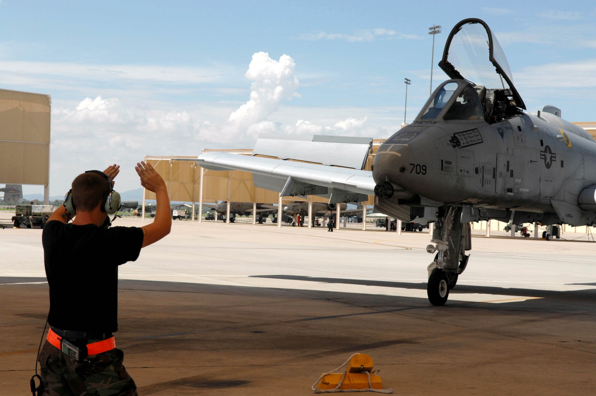Airman 1st Class Peter Strom marshals an A-10 Thunderbolt II piloted by 2nd Lt. Robert Arena who just completed the first A-10C pilot initial qualification course Aug. 2 at Davis-Monthan Air Force Base, Ariz. During the seven-month-long course, the training focused on the new A-10C platform which replaced the A-10A. The pilots also learned the basics of being attack pilot wingmen, which included flying in formation to provide mutual support, communicate with radios and kill the assigned target on the first attempt. Airman Strom is assigned to the 357th Aircraft Maintenance Unit. Lieutenant Arena is an A-10 pilot with the 357th Fighter Squadron. (U.S. Air Force photo/Senior Airman Christina D. Ponte)