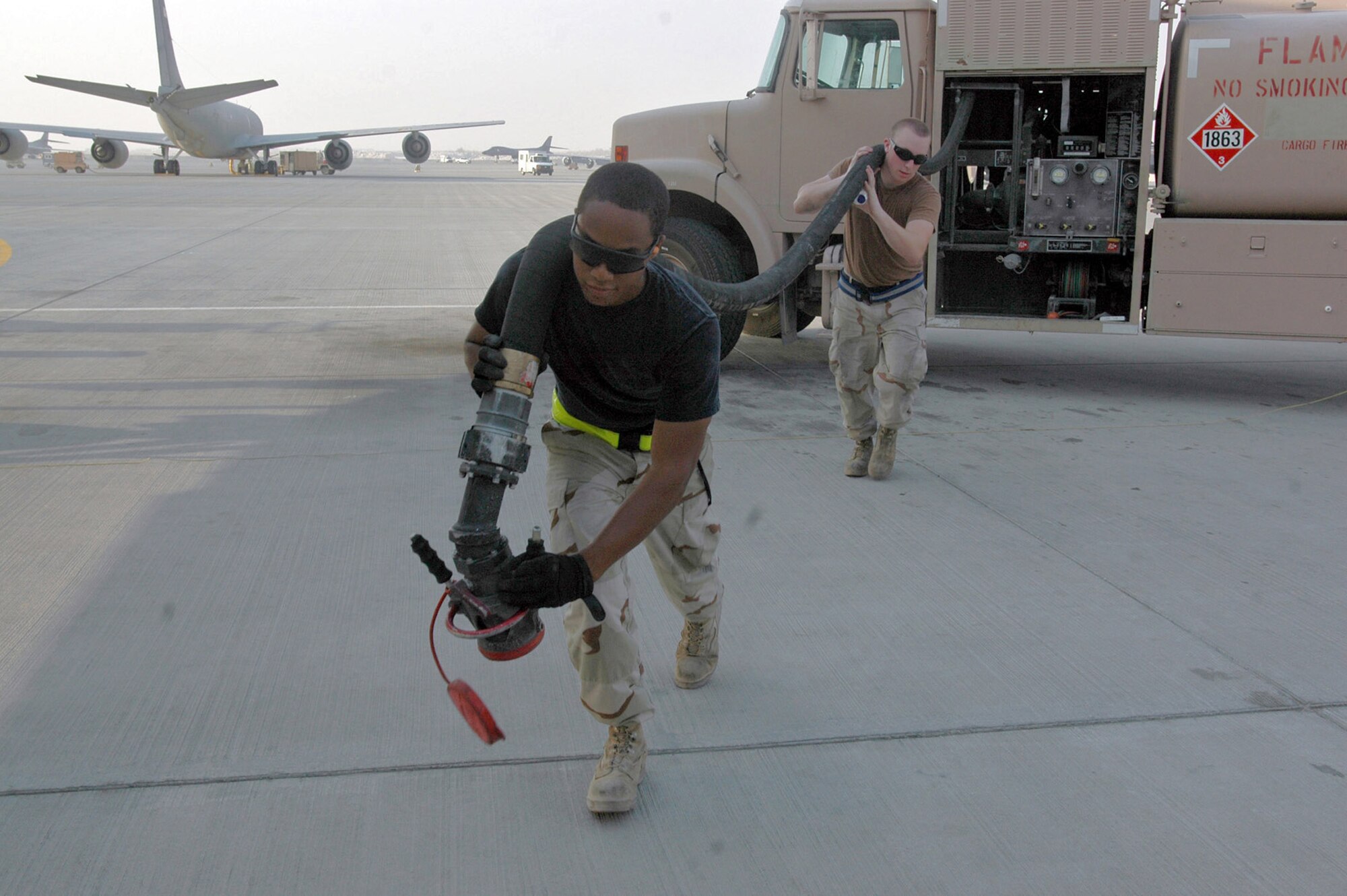 Senior Airman Dustin Dodson, 379th Logistics Readiness Squadron (left) and Senior Airman Ryan McPartland, 340th Aircraft Maintenance Unit heft a fuel line out to a waiting KC-135 Stratotanker in Southwest Asia. The tanker can take between three and four truck loads of fuel before it reaches capacity. The Airmen's units are part of the 379th Expeditionary Aircraft Maintenance Squadron. (U.S. Air Force photo/Senior Airman Clark Staehle)
