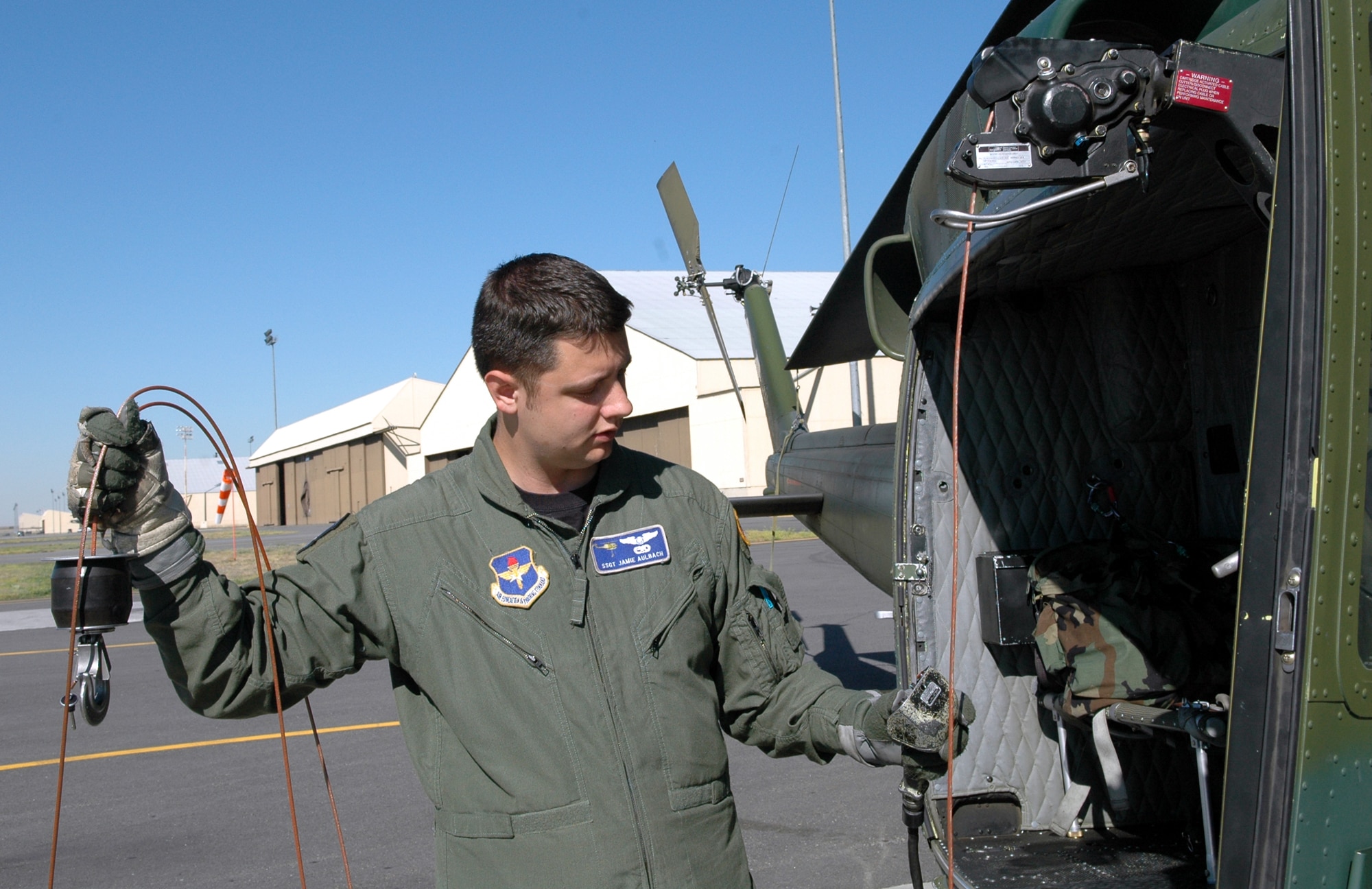 FAIRCHILD AIR FORCE BASE, Wash. -- During pre-flight inspections, Staff Sgt. Jamie Aulbach, 36th Rescue Flight flight engineer, inspects the hoist and cable onboard a UH-1N Huey helicopter. Sergeant Aulbach is responsible for checking the deceleration points in the cable, an action which is completed before every flight that the hoist is going to be used. If the hoist will be used for people, the entire 250-foot cable is checked. (U.S. Air Force Photo / Tech. Sgt. Larry W. Carpenter Jr.)