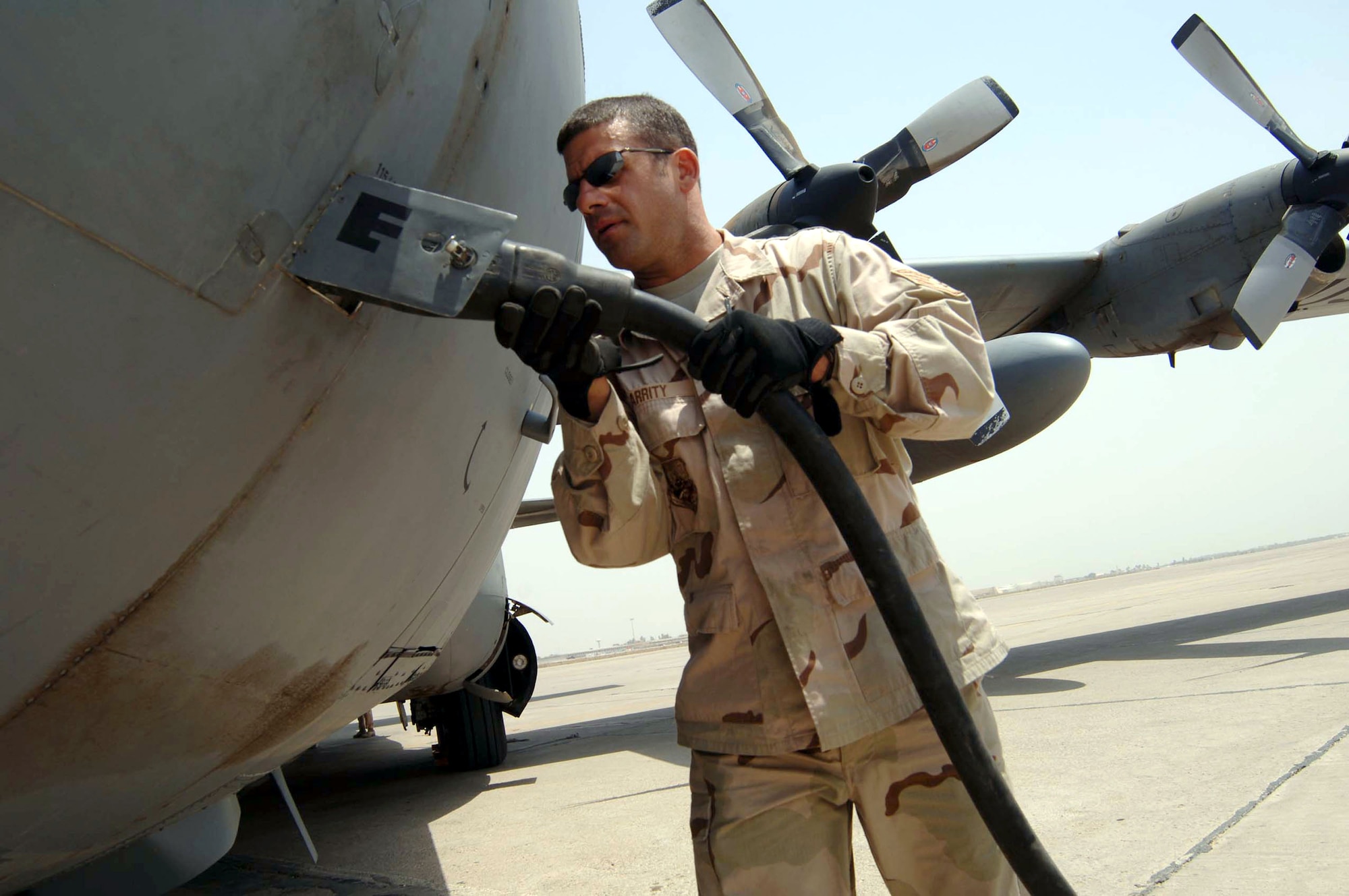 Staff Sgt. David Garrity plugs in external electrical power to a transient C-130 Hercules cargo aircraft July 27 at Baghdad International Airport in Iraq. The 447th Expeditionary Operations Squadron transient alert team coordinates all traffic on the military airfield here. An average day brings in more than 100 fixed and rotary wing aircraft. Sergeant Garrity is a 447th Expeditionary Operations Squadron crew chief. (U.S. Air Force photo/Tech. Sgt. Russell Wicke) 
