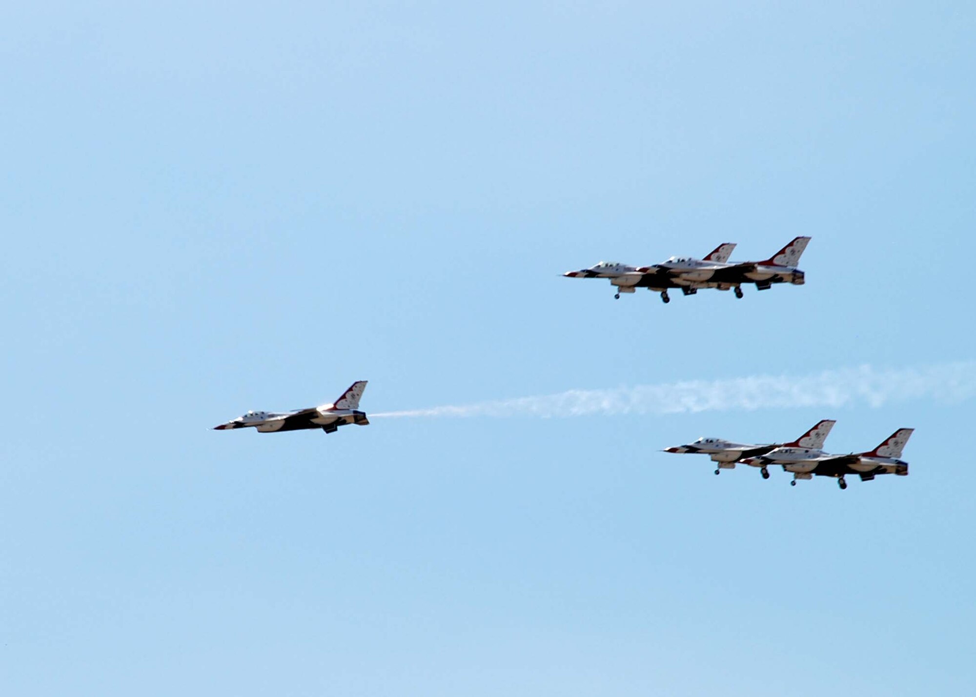 Four Thunderbirds fly by rather slowly, with landing gears down, as a fifth flies through the center at a much greater speed (Photo by Staff Sgt. Chad Thompson).