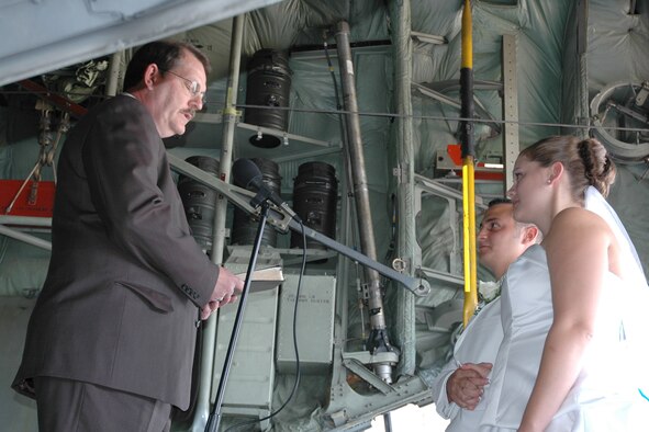 YOUNGSTOWN AIR RESERVE STATION, Ohio - Air Force Reserve Staff Sgt. Kevin Chester and Senior Airman Sarah Savel (right), both assigned to the 757th Airlift Squadron,  say “I do” as Pastor Pete Nash (left) presides over their wedding ceremony held here June 30. The couple exchanged their vows on the tail ramp of a C-130 parked in Hangar 295 in front of a group of family and friends. The newly-wed Staff Sgt. Chester and Senior Airman Chester said they wanted to be married at the base because their assignments here led to their first meeting and to their wedding. After the ceremony, the Chesters, their families and friends gathered at the Mahoning Country Club in Girard, Ohio, for a reception. U.S. Air Force photo/Tech. Sgt. Bob Barko Jr. 