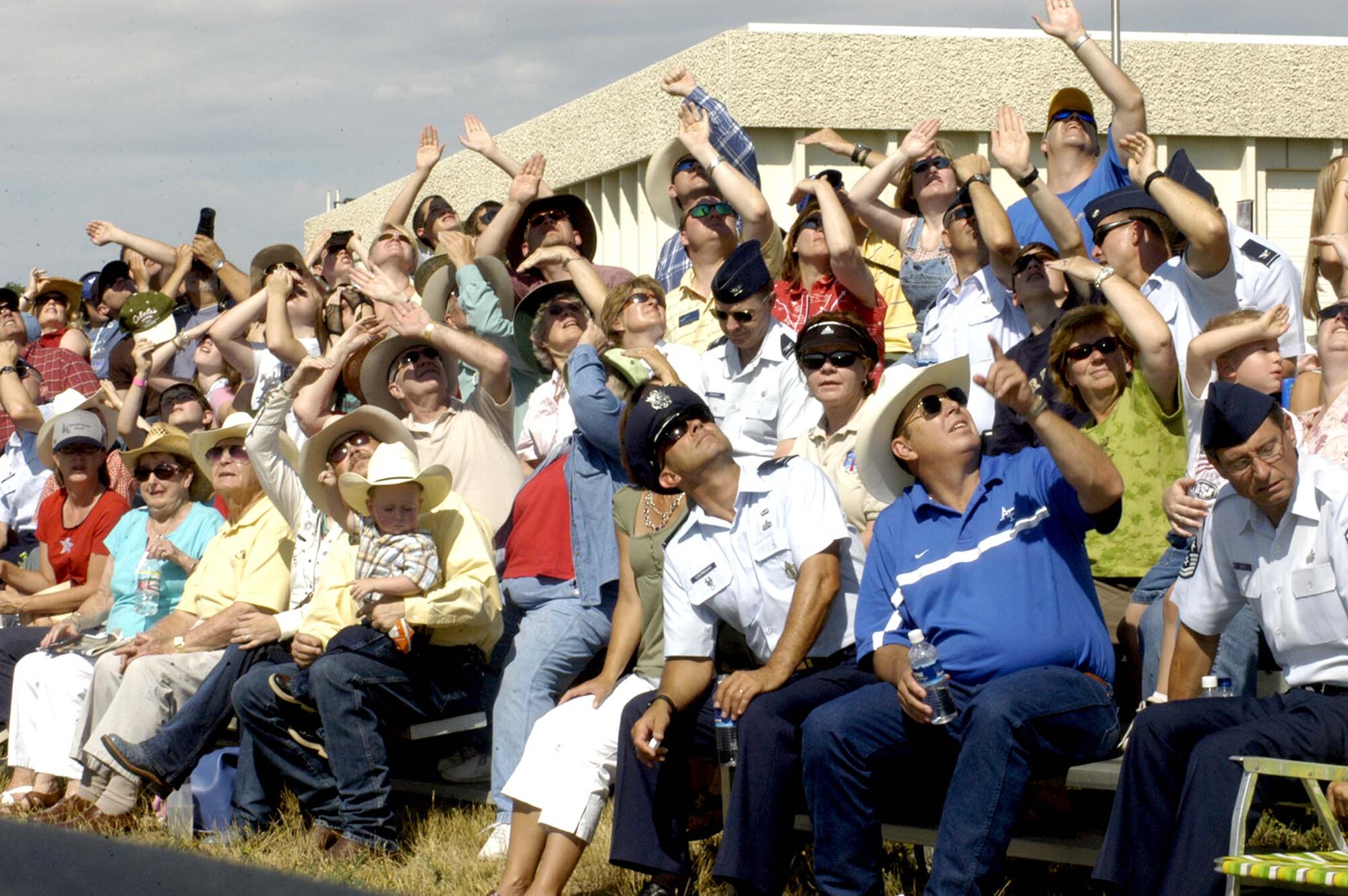 The crowd tries to block out the sun as they watch the Thunderbirds perform an aerial maneuver during the CFD annual air show July 25 at LCCC (Photo by Airman Alex Martinez).