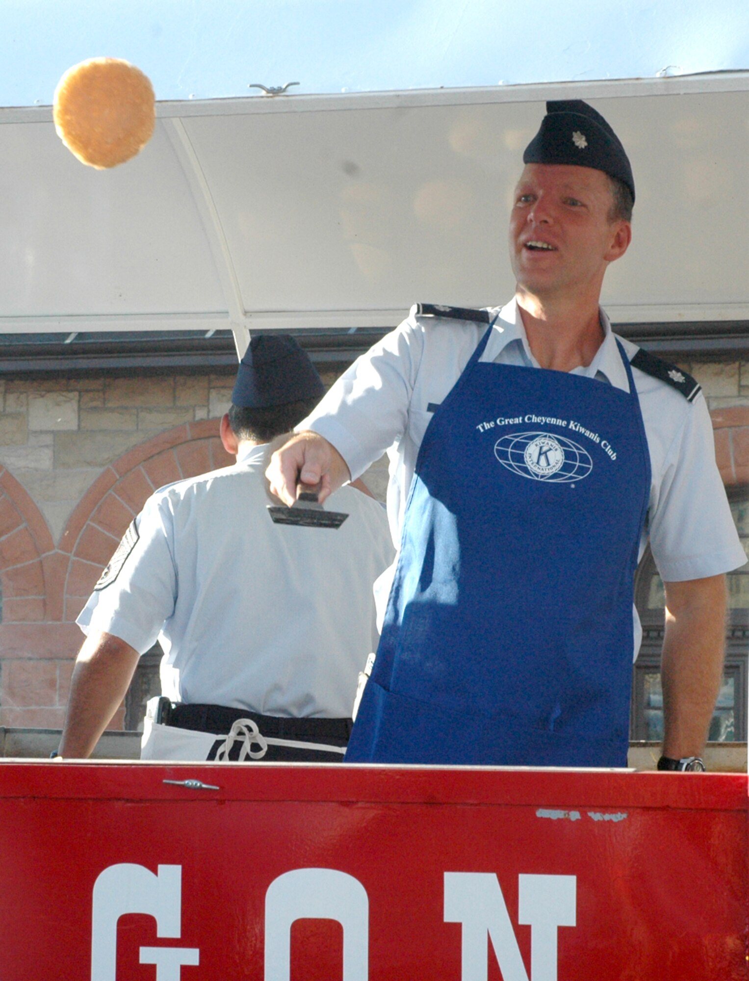 Lt. Col. James Cardinal, 90th Maintenance Group, tosses a pancake to a pancake catcher during a free pancake breakfast at the Cheyenne Depot Plaza July 25. Colonel Cardinal and the rest of the senior staff volunteered to flip pancakes for the free pakcake breakfast (Photo by Airman Alex Martinez).
