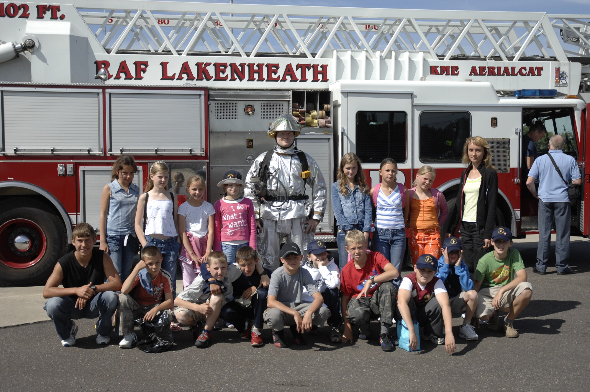 More than 20 Belarusian children huddle around Airman 1st Class Nathan Lobb, 48th Civil Engineering Squadron firefighter here Aug. 3. During their tour of RAF Lakenheath they also viewed a F-15 static display, Memorial Park and viewed a demonstration by the 48th Security Forces Military Working Dogs. The children are in the U.K. through a charity called the Chernobyl Children Lifeline. The charity was founded for the children of Belarus, which is a developing country that suffered most from the fall-out caused by the Chernobyl nuclear accident in 1986. (Photo by U.S. Air Force Airman 1st Class Erika Brooke) 