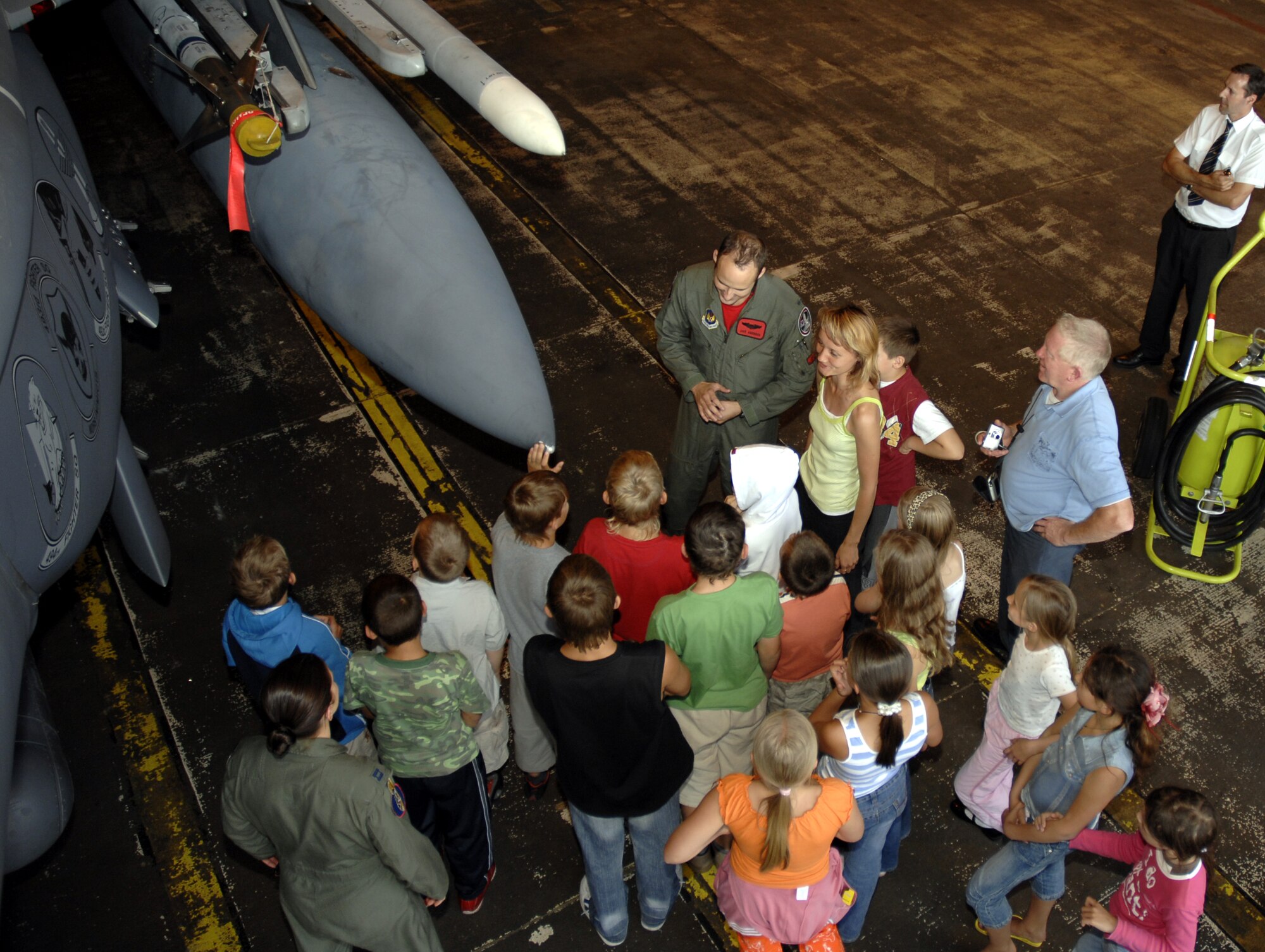 More than 20 Belarusian children huddle around 1st Lt. Jacob Anderson, 494th Fighter Squadron pilot, as he talks about the F-15 E Strike Eagle here Aug. 3. During their tour of RAF Lakenheath they also toured the 48th Civil Engineer Squadron fire station, Memorial Park and viewed a demonstration by the 48th Security Forces Military Working Dogs. The children are in the U.K. through a charity called the Chernobyl Children Lifeline. The charity was founded for the children of Belarus, which is a developing country that suffered most from the fall-out caused by the Chernobyl nuclear accident in 1986. (Photo by U.S. Air Force Airman 1st Class Erika Brooke) 