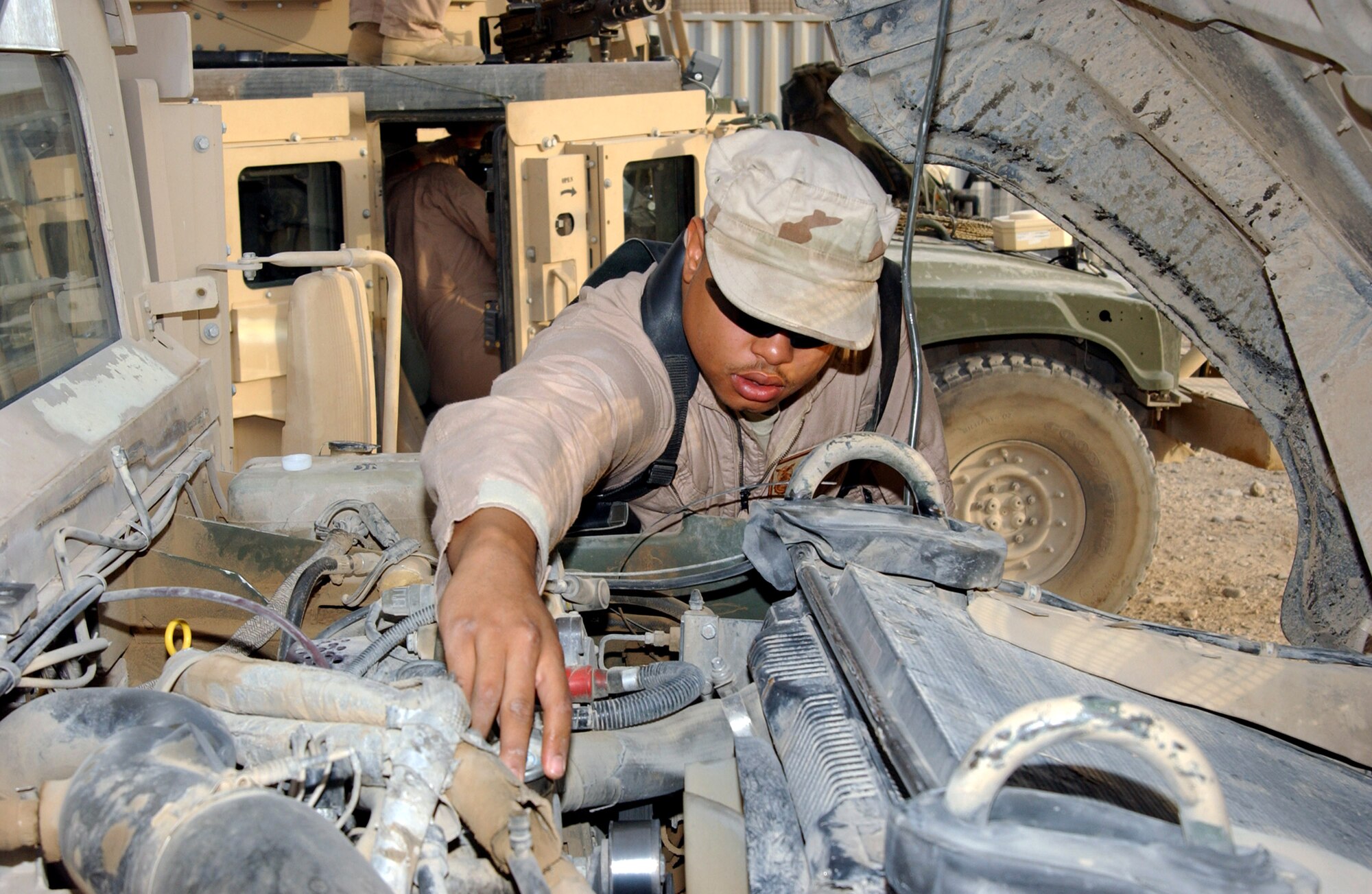 Senior Airman Christian Carithers checks the fluid levels in a Humvee while preparing for another mission outside the wire with his police transition team in July at Contingency Operating Base Speicher, Iraq. Deployed from McGuire Air Force Base, N.J., Airman Carithers is assigned to the 732nd Expeditionary Security Forces Squadron Det. 1. Members of the police transition team check the vehicles thoroughly to ensure they will perform properly. The police transition team's goal is to help the Iraqis establish a functioning, independent police force. (U.S. Air Force photo/Master Sgt. Steve Horton) 
