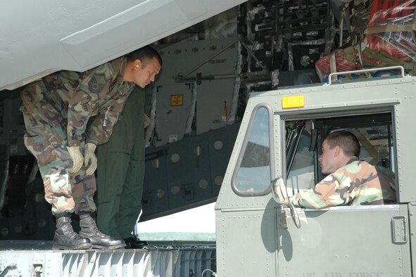 YOUNGSTOWN AIR RESERVE STATION, Ohio - Air Force Reserve Master Sgt. Victor Rivera instructs Airman 1st Class Trevor Merrow as he pulls a 60K aircraft loader into position behind a C-17 cargo aircraft. Both airmen are assigned to the 76th Aerial Port Squadron here and were involved in loading nearly nine tons of educational supplies being sent to four rural schools in Belize, Central  America. The airlift of school supplies is for a Denton Program humanitarian effort by the "Mission of Love Foundation," a non-profit orgaization based in Youngstown, Ohio. U.S. Air Force photo/Tech. Sgt. Bob Barko Jr.  