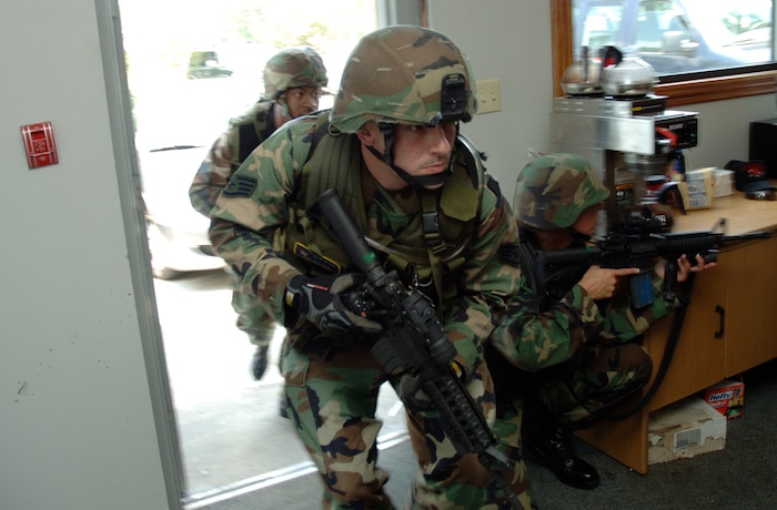 Staff Sgt. Richard Guay, Tech. Sgt. Heather Huckins and Senior Airman Brien Oxford, 437th Security Forces Squadron Phoenix Ravens, storm through the door where the hostages are being held during the basewide exercise on Charleston AFB Aug. 1. (U.S. Air Force Photo/Staff Sgt. April Quintanilla)