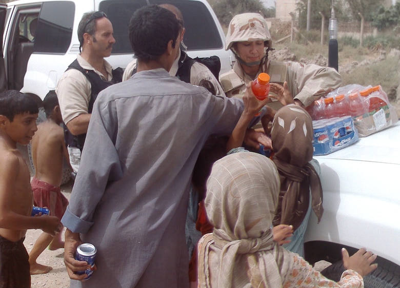 Lt. Col. Linda K. Bethke and members of her convoy hand out drinks to Iraqi children. (Courtesy photo)