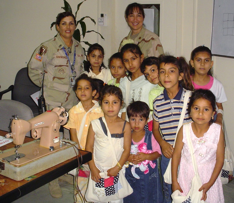 Lt. Col. Linda K. Bethke (right), 11th Contracting Squadron commander, and Army Sergeant 1st Class Maggie Hammonds pose with a group of Iraqi children they taught to quilt. (Courtesy photo)