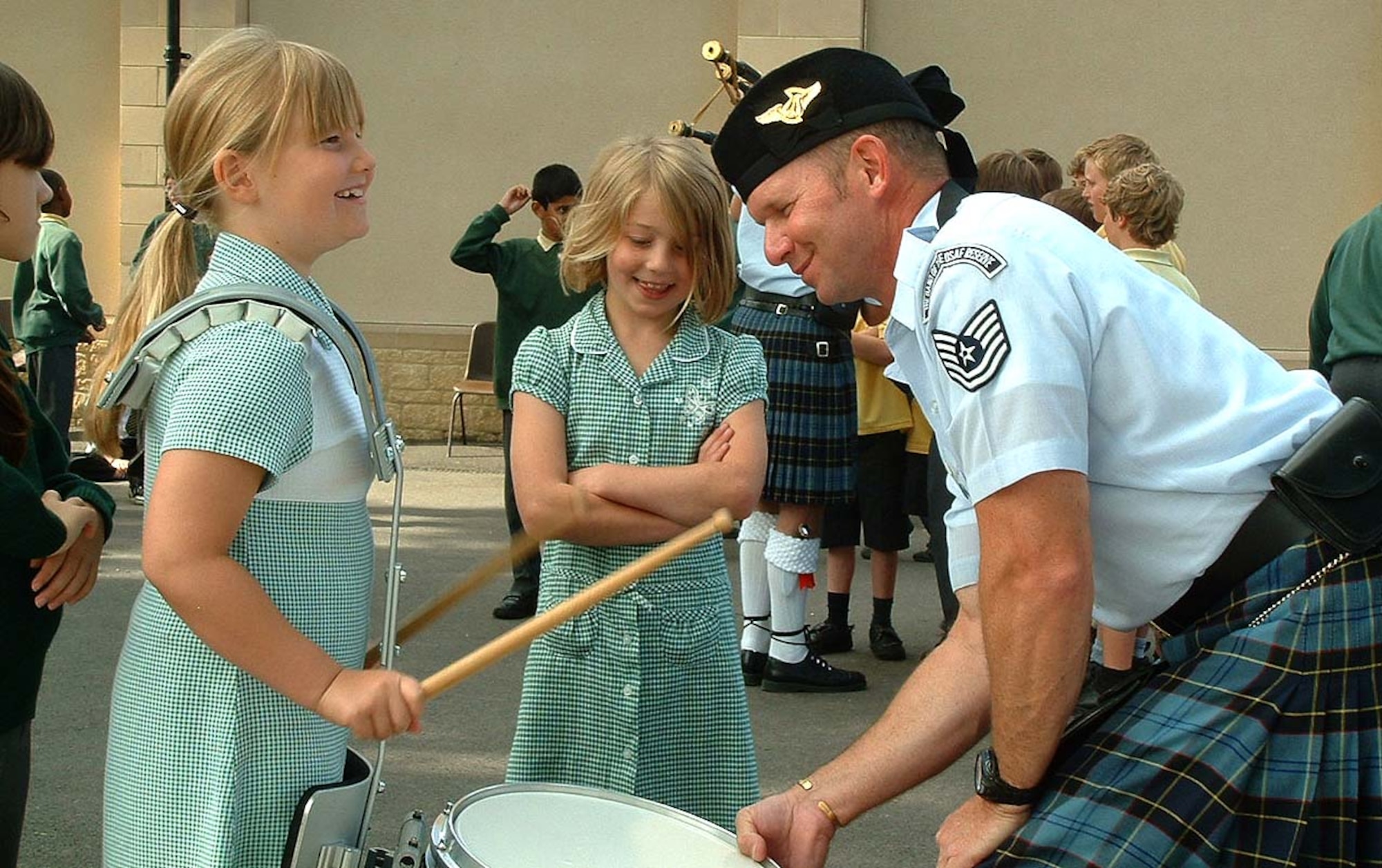 FAIRFORD, United Kingdom -- Tech. Sgt. Jeff Bare gives a student at the Kempford School here a chance to play the pipe drum during a visit and performance. The U.S. Air Force Reserve Pipe Band was in England to participate in the Royal International Air Tattoo and took some time to perform at seven schools surrounding the base and also receive training at (Royal) Army School of Bagpipe Music and Highland Drumming in Edinburgh, Scotland. (U.S. Air Force photo/Staff Sgt. Eric Frank)
