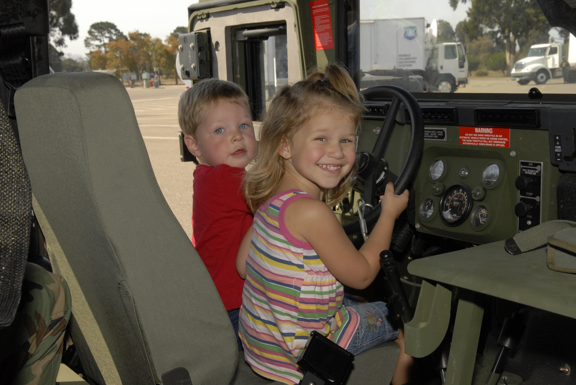 VANDENBERG AIR FORCE BASE, Calif. -- Josh Braxton, 2, and Hailey Bolles, 3, mock test drive an armored humvee during the 30th Space Wing Touch-a-Truck event on Aug. 4.  The Touch-a-Truck event is sponsored every year by the 30th Services Division to allow parents and their children to get a hands on look at fire engines, armored humvees, loaders, 30-ton aircraft cargo loaders and transporters, and launch vehicle tracking stations work. (U.S. Air Force photo/Airman 1st Class Adam Guy)