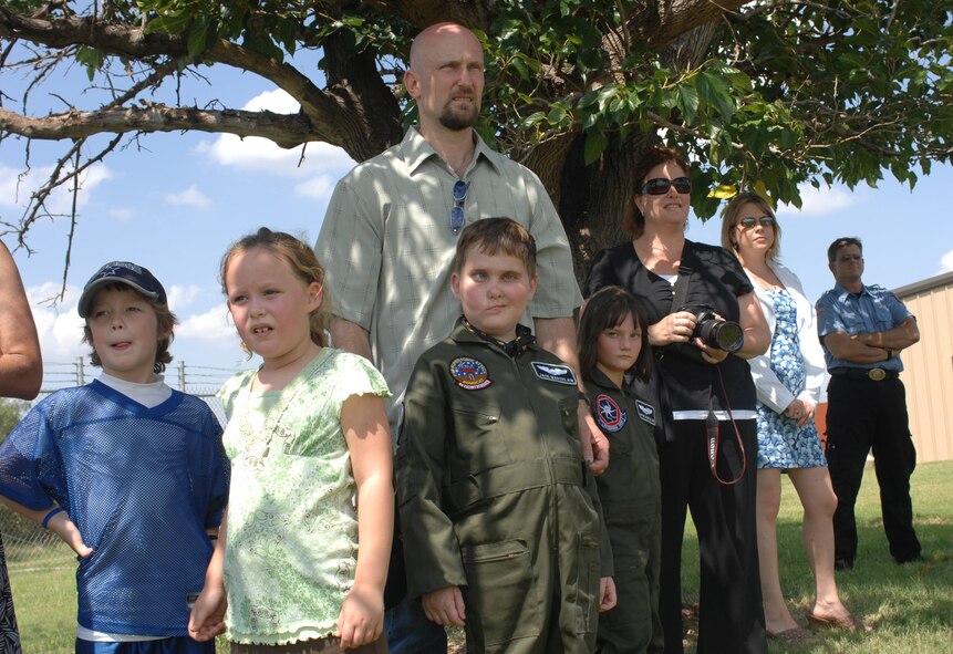 Jack Marcelain (center), along with his friends and family share a moment as they watch a military working dog demonstration by the 7th Security Forces August 1. Jack was diagnosed with a tumor at the base of his brain stem in April 2005. His family and friends participated in the Pilot For a Day program, which allows childeran with serious medical conditions to experience what its like to be in the Air Force.