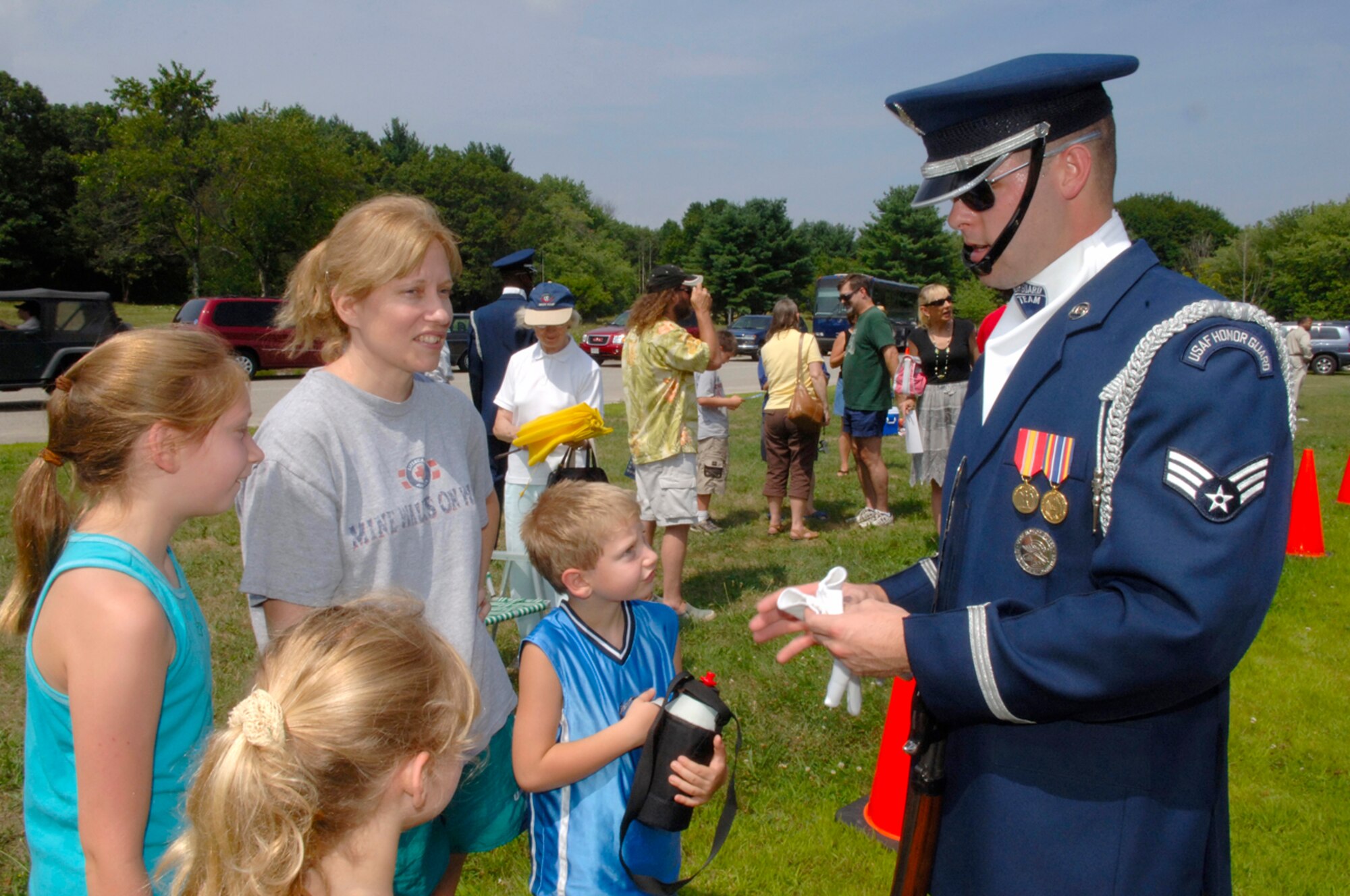 HANSCOM AFB, Mass. -- Air Force Honor Guard Drill Team member Senior Airman James Cashwell chats with Brenda Huff, wife of Capt. Richard Huff, and their children Rebecca, 11, Sarah, 7, and Jake, 6, following a Drill Team performance in Minute Man National Historical Park in Lexington, Mass. Aug. 7. The Huff family recently relocated to Hanscom. The Drill Team conducted two performances during their visit to the base. On Aug. 6 the Drill Team performed on base for the base populace; on Aug. 7 the Drill Team performed for the public in the park. (U.S. Air Force photo by Jan Abate)