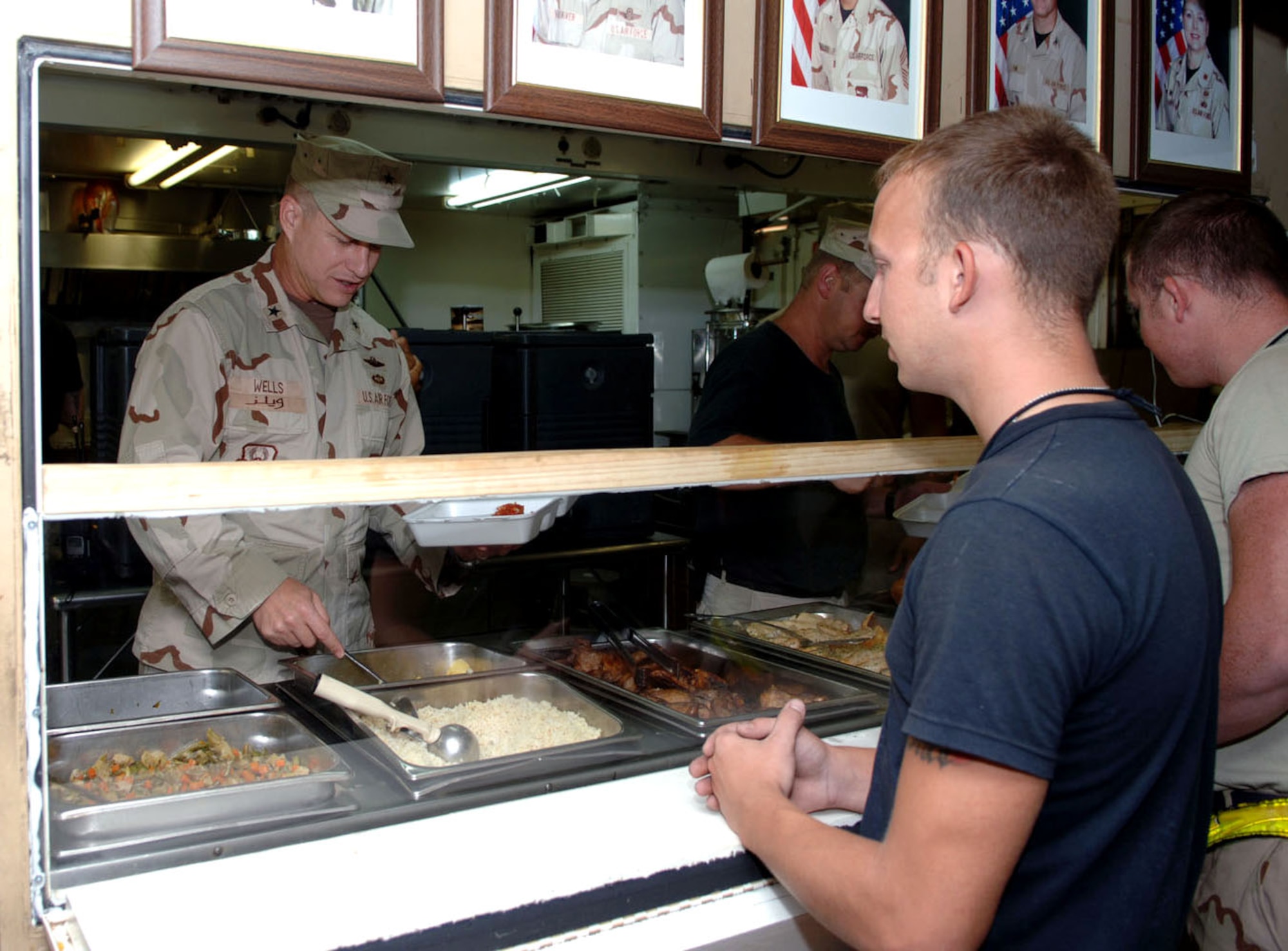 Brig. Gen. Lawrence Wells, the 380th Air Expeditionary Wing commander, dishes up a meal for a diner Aug. 7 at the containerized deployable kitchen. The general and members of his staff served food at the CDK all week to show their appreciation for the hard work and efforts put in on the operational side of base. (U.S. Air Force photo/Airman 1st Class Matthew Cook)