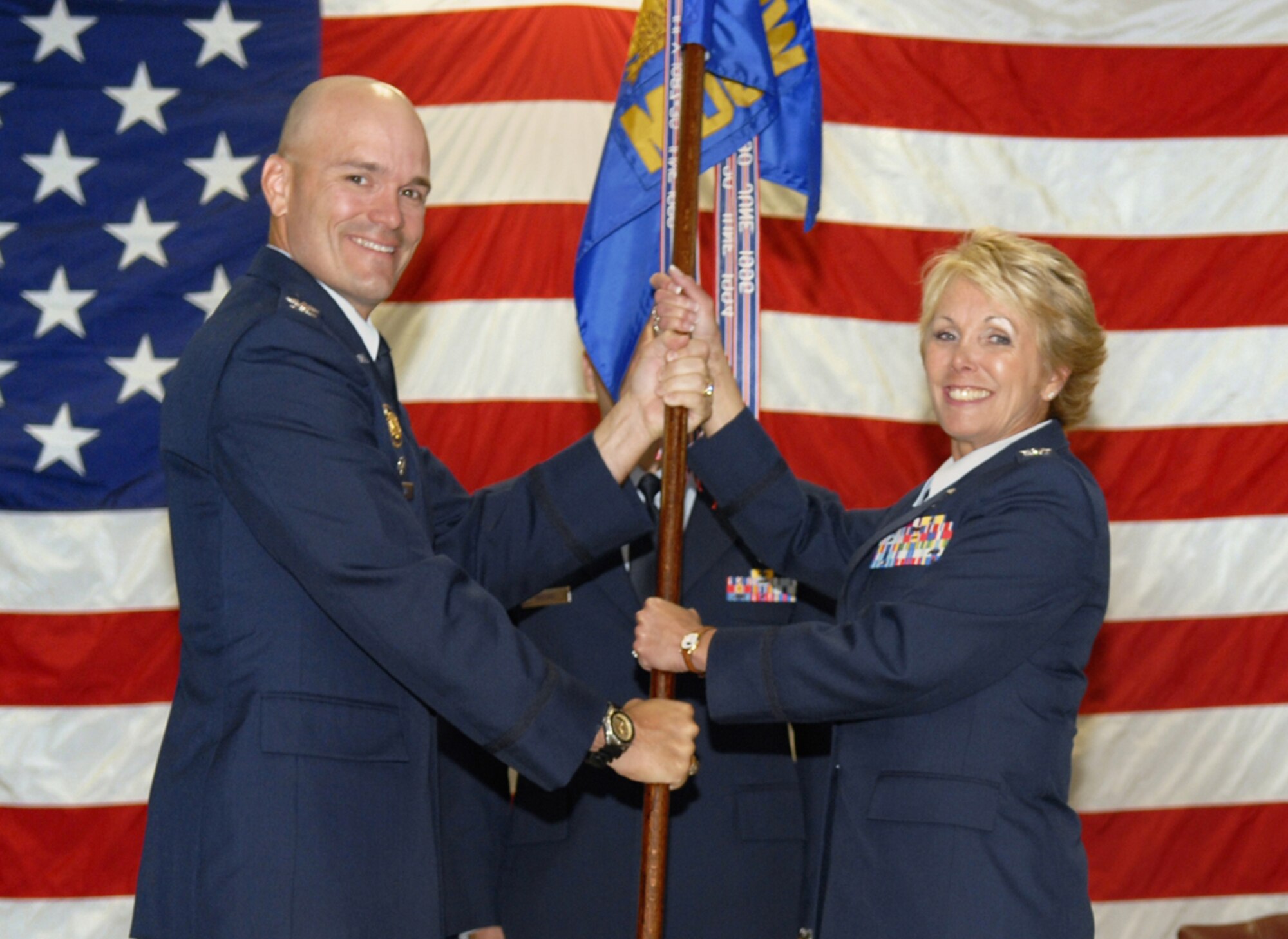 Col. Carlton Everhart, 97th Air Mobility Wing commander, hands command of the 97th Medical Group to Col. Cheryl E. Gregorio, previously the Director of Health Service Operations at Peterson Air Force Base. (U.S. Air Force photo/Senior Airman Joshua Demotts)