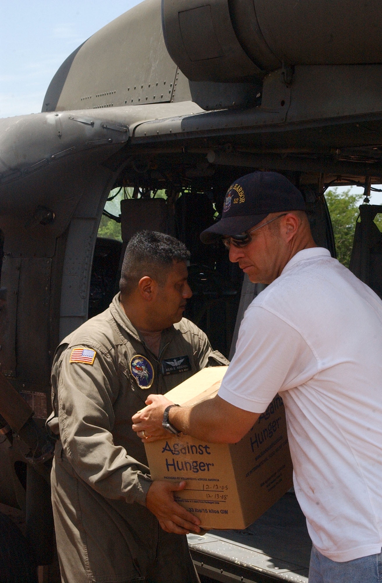Navy Chaplain (Lt.) Dennis Wheeler, right, from the USS Pearl Harbor hands Army Sgt. First Class Julio Ascencio, a crew chief with the 1st Battalion 228th Aviation Regiment at Soto Cano Air Base, Honduras a box of humanitarian supplies to load into a UH-60 Black Hawk. The supplies were transported to villiages in southern Honduras as part of Project Handclasp, a partnership between the Navy and corporations, public service organizations, non-government organizations and individuals throughout the United States to provide humanitarian assistance overseas. Members of Joint Task Force-Bravo assisted the Navy with logisitics, ground and air support. Air Force photo by Senior Airman Shaun Emery.                                                     