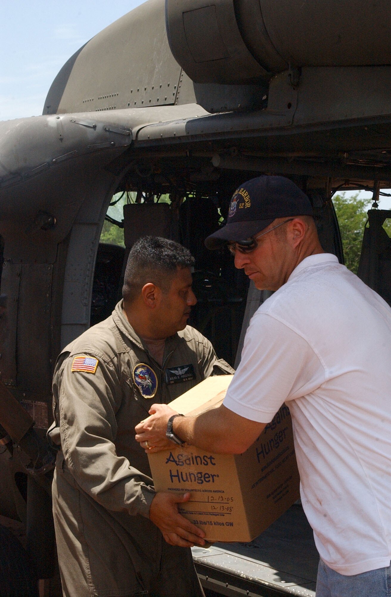 Navy Chaplain (Lt.) Dennis Wheeler, right, from the USS Pearl Harbor hands Army Sgt. First Class Julio Ascencio, a crew chief with the 1st Battalion 228th Aviation Regiment at Soto Cano Air Base, Honduras a box of humanitarian supplies to load into a UH-60 Black Hawk. The supplies were transported to villiages in southern Honduras as part of Project Handclasp, a partnership between the Navy and corporations, public service organizations, non-government organizations and individuals throughout the United States to provide humanitarian assistance overseas. Members of Joint Task Force-Bravo assisted the Navy with logisitics, ground and air support. Air Force photo by Senior Airman Shaun Emery.                                                     