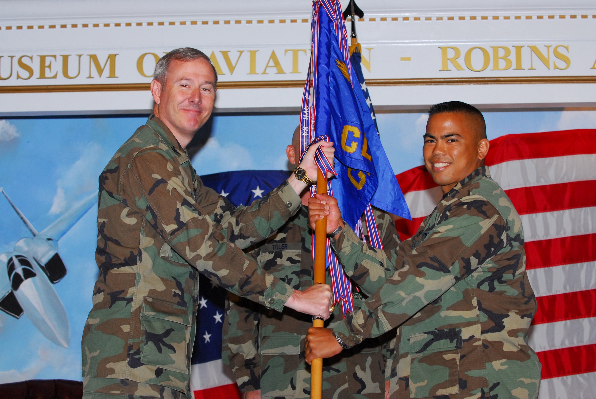 Col. Scott A. Miller, 402nd AMXG commander passes the guidon to Maj. Michael H.M. Egbalic as he becomes commander of the 653rd Combat Logistics Support Squadron at a change of command ceremony July 26 at the Museum of Aviation's Century of Flight Hangar. Maj. Egbalic replaces Maj. Paul Kanning. U. S. Air Force photo by Eric Palmer