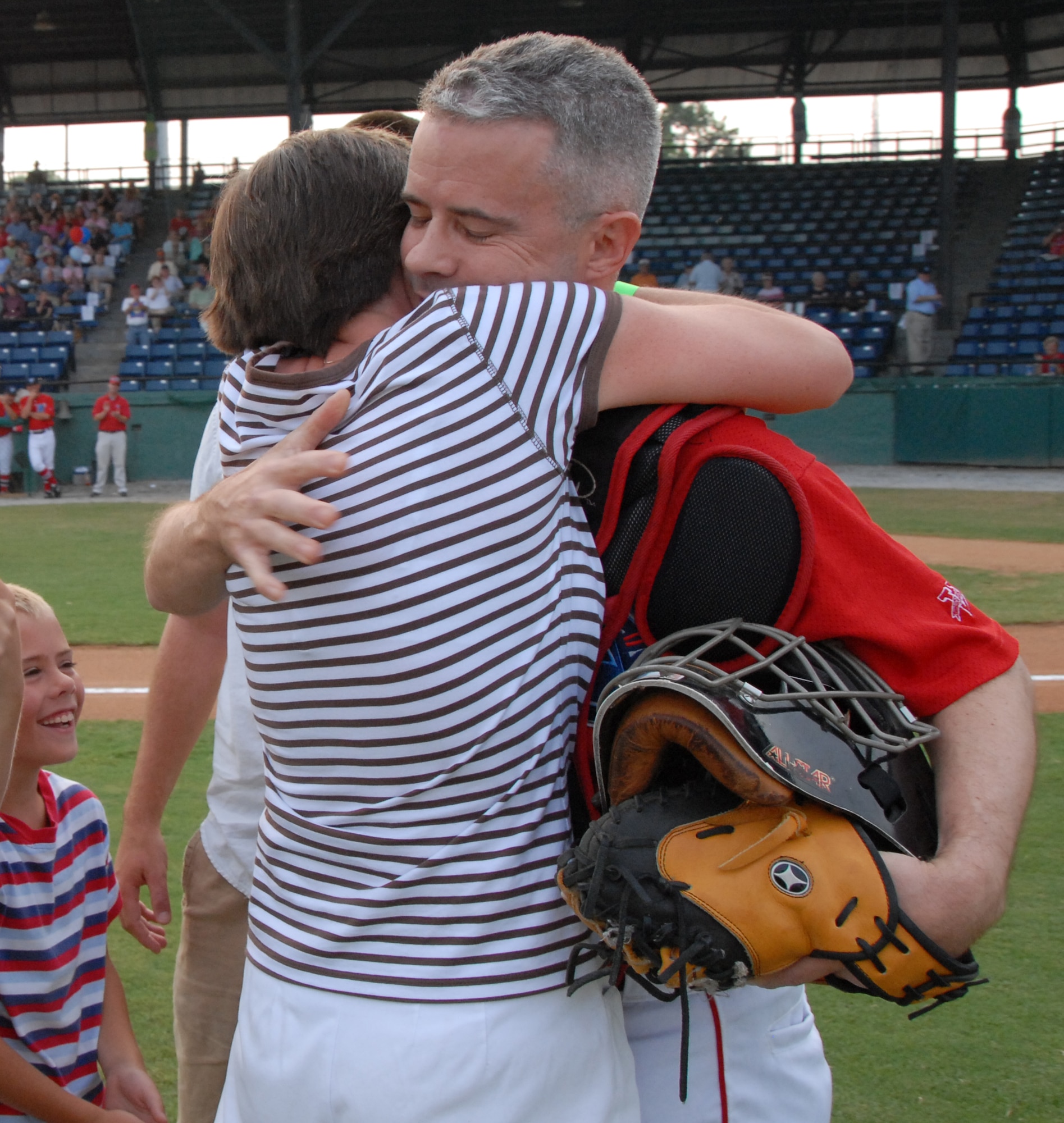 Lt. Col. Mark Wade hugs his wife Joan during opening ceremonies of the Macon Music game Monday night. Col Wade, who has been deployed for six months surprised his family after being disguised as a Macon Music catcher. U. S. Air Force photo by Sue Sapp