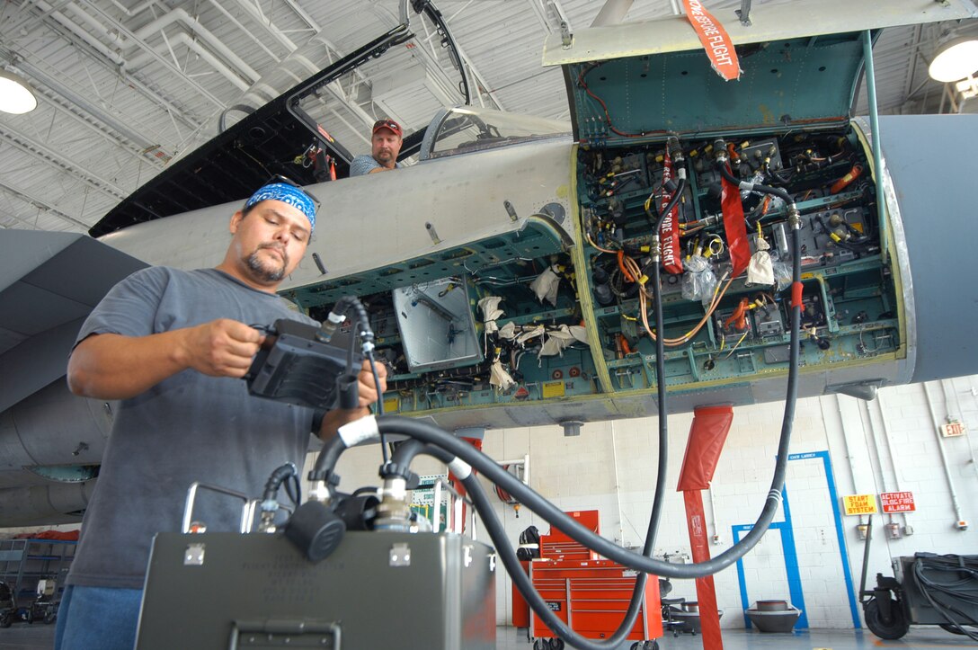 John Hysell and Henry Sparks, aircraft mechanics, get a  look at one of the automated flight test control systems during a demonstration Aug 1. The tester plugs into the F-15, like hooking up a car engine to a computer to discover engine trouble. U.S. Air Force photo by Sue Sapp   