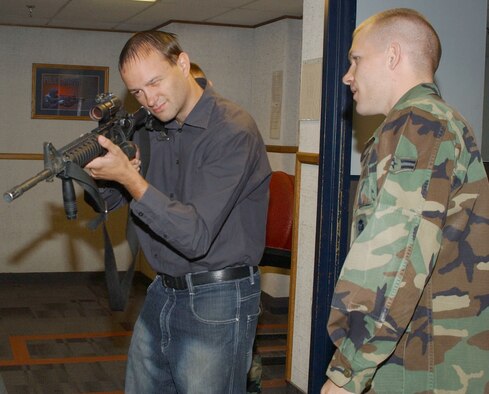 Ryan Hall, Great Falls Tribune night communities editor, learns about the M4 Carbine, which is the primary weapon for all security forces here, from Airman 1st Class Trevor Low, 341st Security Forces Support Squadron. The Tribune staff were given a mission briefing from wing leadership, learned about a missileer's day-to-day responsibilities and also toured a missile maintenance facility Aug. 8.  (U.S. Air Force photo/Senior Airman Eydie Sakura).            