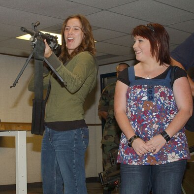 Stacy Byrne, Great Falls Tribune features reporter, gets a kick out of holding a M249 machine gun, as Jane Arbuthnot, a Tribune intern, stands by and smiles. The Tribune staff were given a mission briefing from wing leadership, learned about a missileer's day-to-day responsibilities and also toured a missile maintenance facility Aug. 8. (U.S. Air Force photo/Senior Airman Eydie Sakura).                  