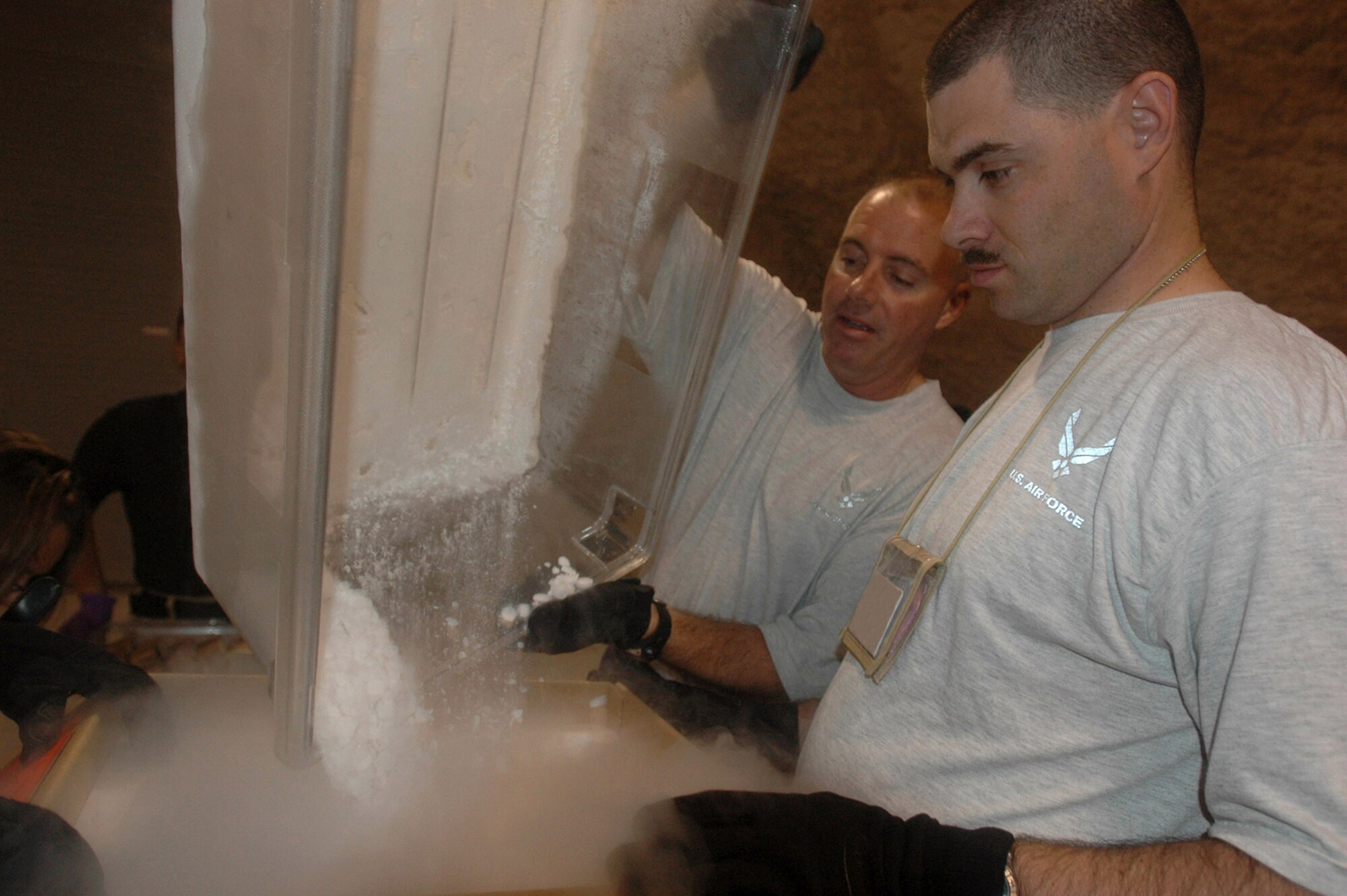 Senior Master Sgt. Scott Graham (left) pours dry ice into a shipping container while Staff Sgt. Joel Ketchum prepares to seal the box Aug. 4 in Southwest Asia. The shipping containers are made of insulated foam to help keep the blood components cool until they reach their final destination. Sergeants Graham and Ketchum are assigned to the 379th Air Expeditionary Wing. (U.S. Air Force photo/Senior Airman Clark Staehle) 
