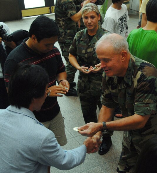 OSAN AIR BASE, Republic of Korea -- OSAN AIR BASE, Republic of Korea -- Lt. Gen. Stephen G. Wood, 7th Air Force commander, hands out coins to Gwacheon High School students at the Officers' Club here Tuesday. During a tour of Osan, the students also viewed several aircraft, learned about various fire fighting equipment and recieved a brief on Osan's mission in the Republic of Korea. (U.S. Air Force photo by Senior Airman Eunique Stevens)