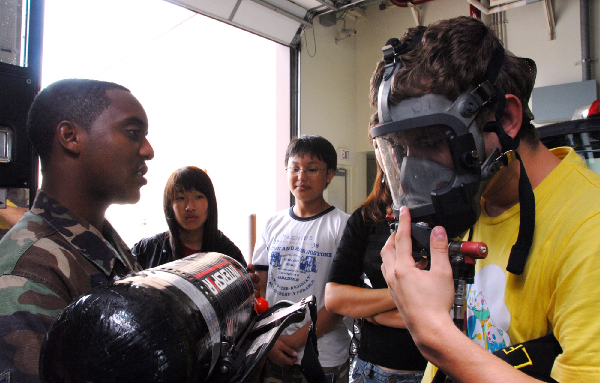 OSAN AIR BASE, Republic of Korea -- Senior Airman Nathaniel Andrews, 51st Civil Engineering Squadron firefighter, shows Gwacheon High School students a self-contained breathing apparatus during a tour here Tuesday. The students also viewed several aircraft, learned about various fire fighting equipment and recieved a brief on Osan's mission in the Republic of Korea. (U.S. Air Force photo by Senior Airman Eunique Stevens