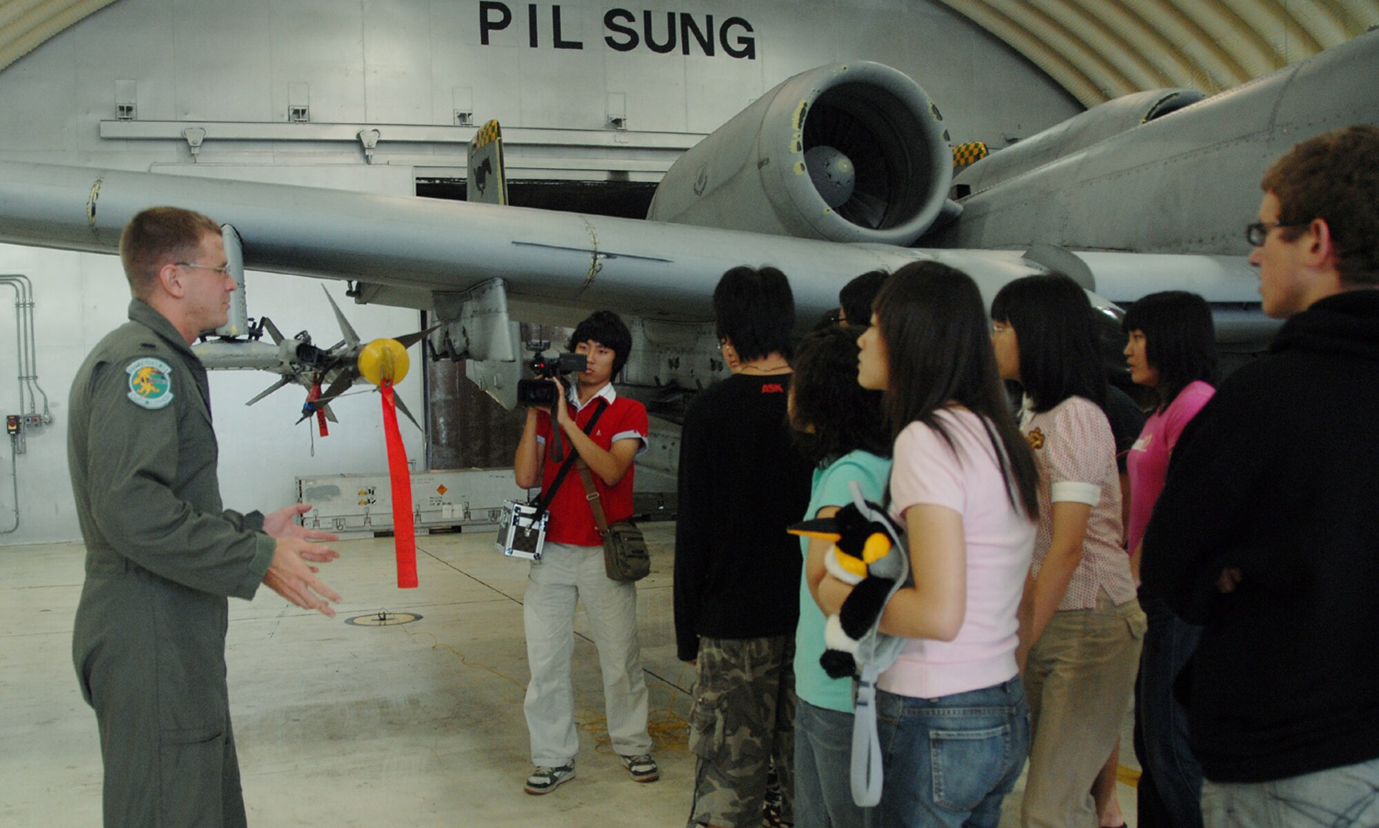 OSAN AIR BASE, Republic of Korea -- First Lieutenant Abram Burk, 25th Fighter Squadron pilot, briefs Gwacheon High School students on the design and capabilities of the A-10 Thunderbolt II during a tour here Tuesday. The students also got to see the F-16 Fighting Falcon, learned about various fire fighting equipment and were briefed on Osan's mission in the Republic of Korea. (U.S. Air Force photo by Senior Airman Eunique Stevens)