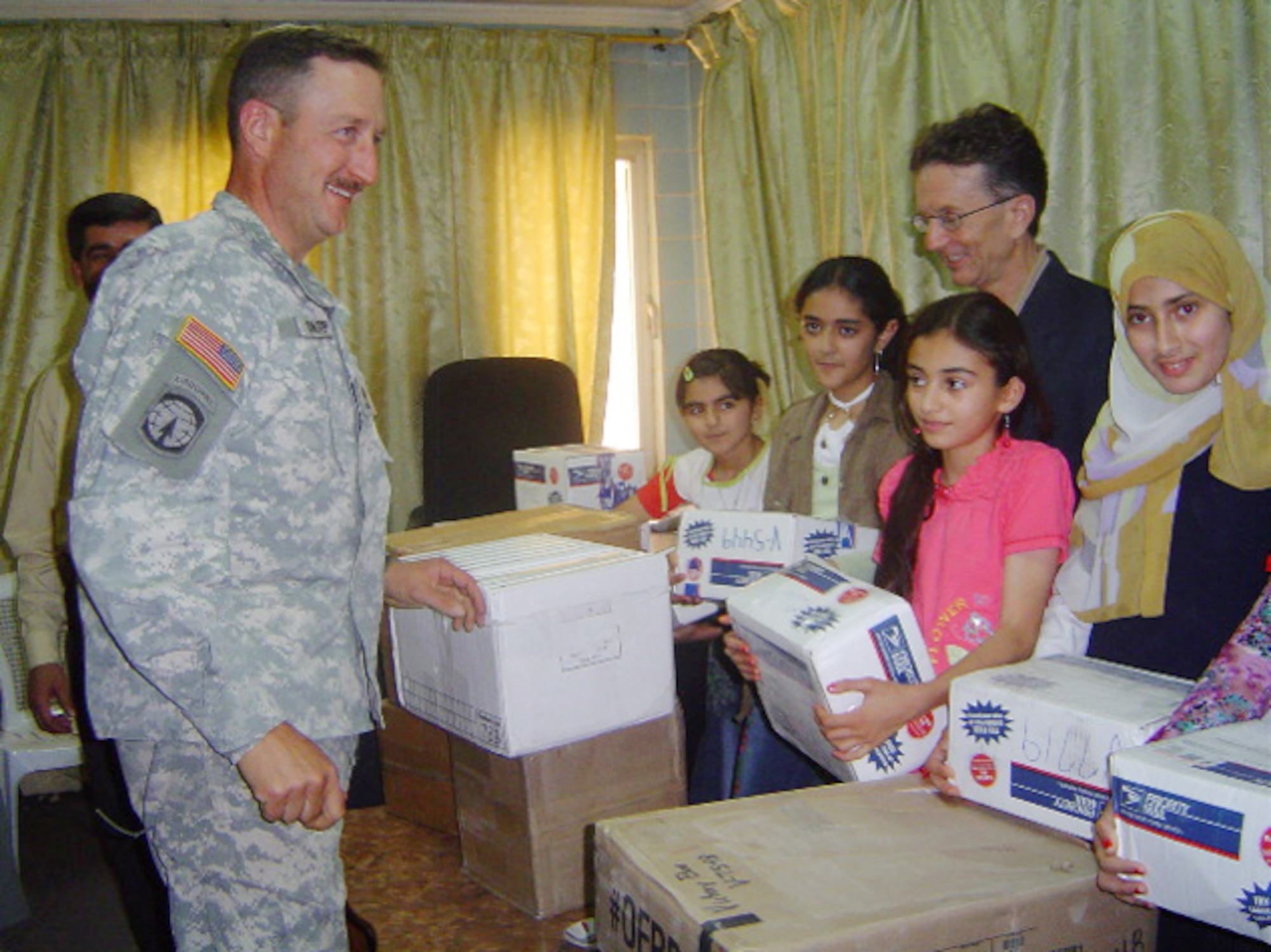 A Soldier helps distribute Victory Boxes to a group of girls in Tikrit, Iraq. Victory Boxes is a national program that gives citizens and servicemembers empty mailing boxes addressed to military members serving in Iraq and Afghanistan. Participants then fill the boxes with school supplies, used toys, clothes and more, and ship them overseas (U.S. Air Force photo) 