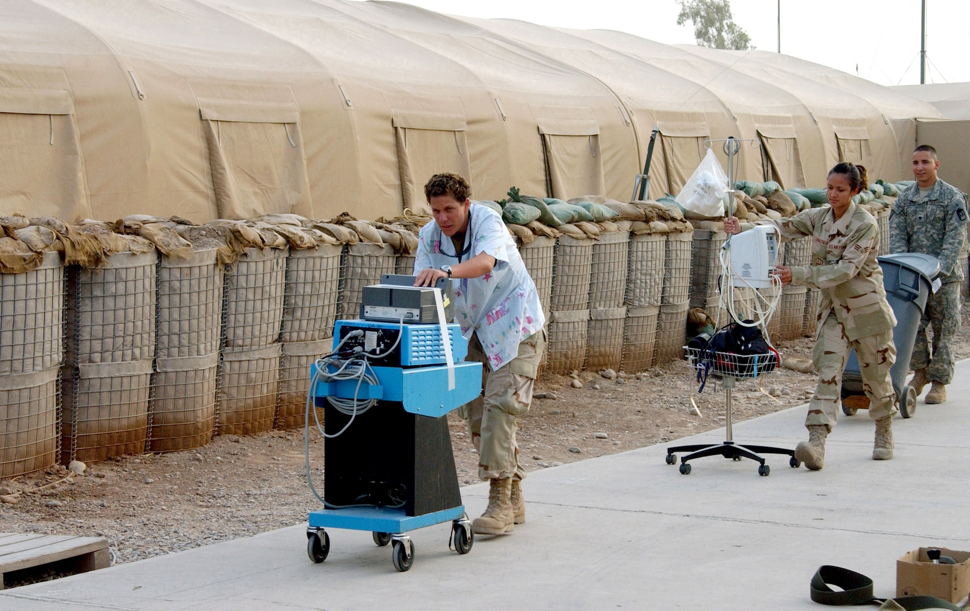 Staff Sgt. Tanja Green, Senior Airman Jacklynn Levasseur and Army Spc. Ivan Nazario move equipment from the 332nd Expeditionary Medical Group's Air Force Theater Hospital's tent facility to its newly upgraded, pre-engineered facility at Balad Air Base, Iraq, Aug. 3. Sergeant Green is a surgical technician, and Airman Levasseur and Specialist Nazario are radiology technicians assigned to the 332nd EMDG. (U.S. Air Force photo/1st Lt. Shannon Collins) 