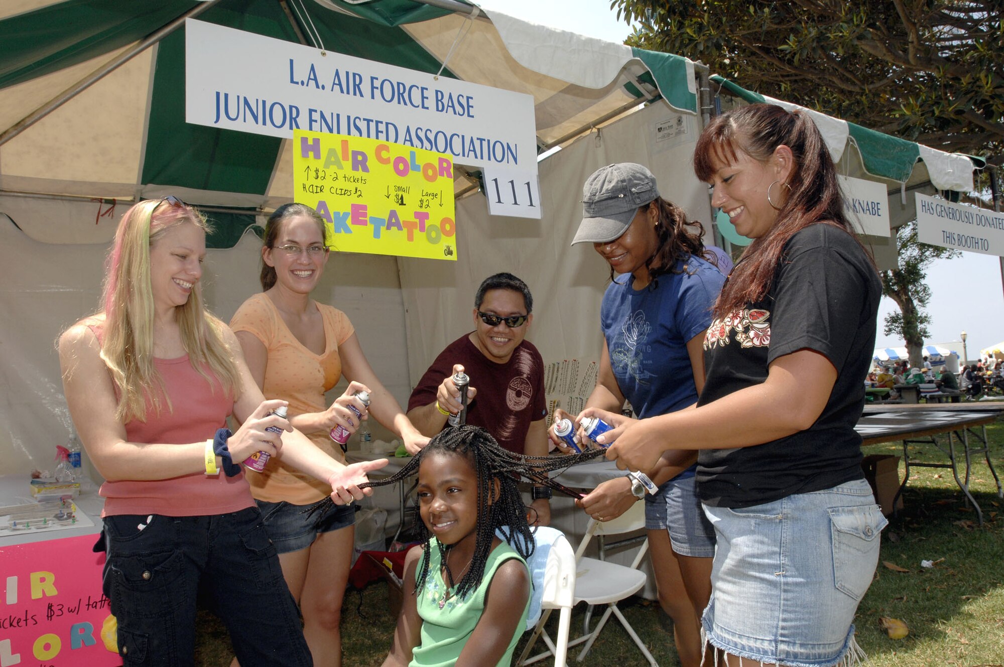 A record-breaking crowd enjoyed the “Taste in San Pedro's” outdoor fest of live music, diverse food and retail sales booths this last weekend at Point Fermin Park.  Pictured here are junior enlisted volunteers from Los Angeles Air Force Base "painting" a little girl's hair.  (Photo by Lou Hernandez.)