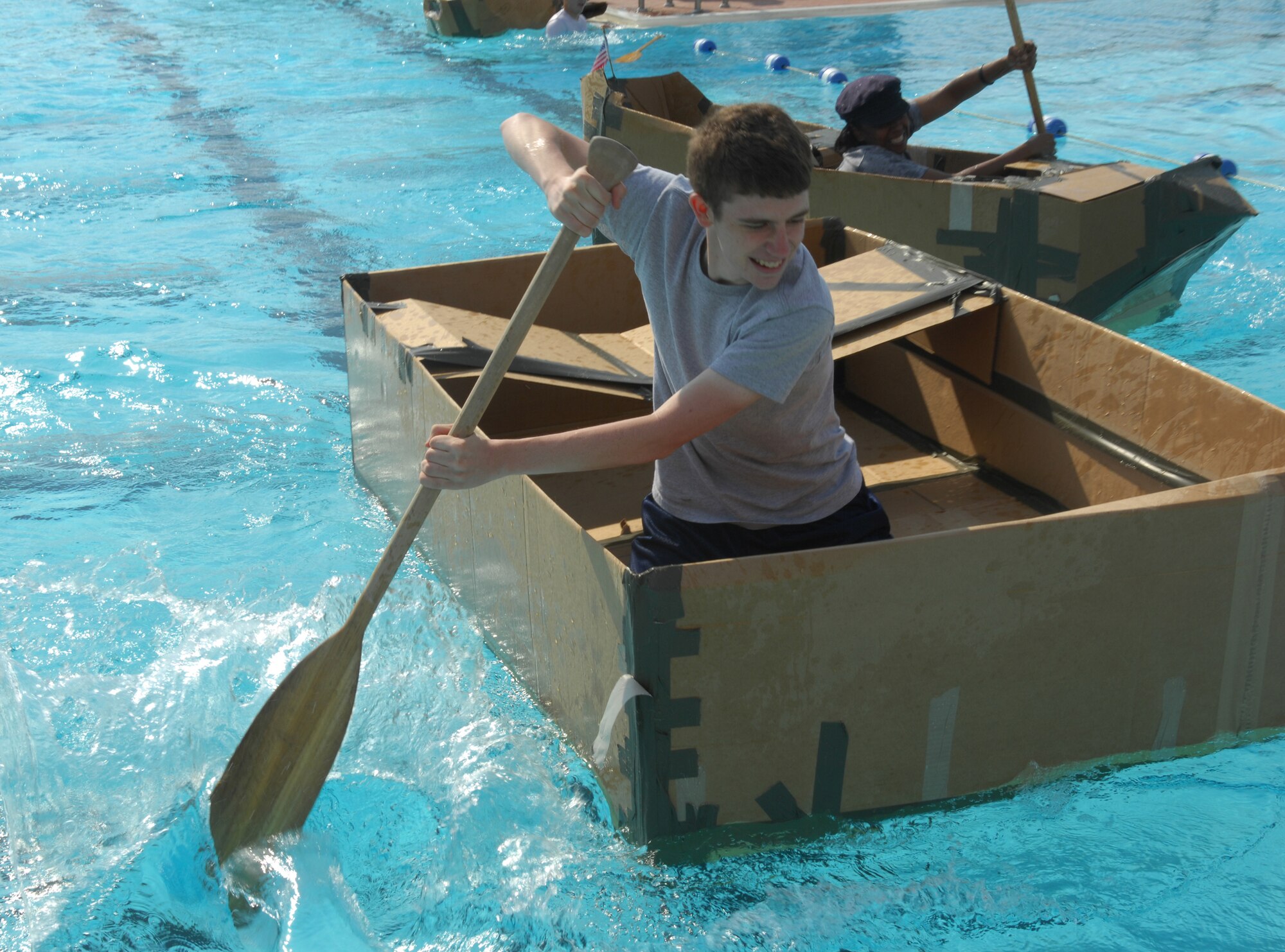 MINOT AIR FORCE BASE, N.D. -- Airman 1st Class Colby Citte, 5th Communications Squadron, skipper's the 5th CS's cardboard boat to victory during the Sports Day build-a-boat contest here Aug 10. Participating units were required to build a boat using only duct tape and cardboard, and race across the base outdoor pool. Sports day is a day set aside for units to participate as a group in various sporting activities. (U.S. Air Force photo by Airman 1st Class Sharida Bishop)
