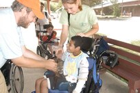 Eight-year-old Marty grins as Camp CAMP volunteer Jarer Hrdina from the Czech Republic hands him a ferret and counselor Julie Ness watches. The campers, who have limited to no verbal communication or self-help skills, enjoy the petting zoo at Camp CAMP along with other traditional camping experiences. (USAF photo by Lilly Flores-Janecek)    