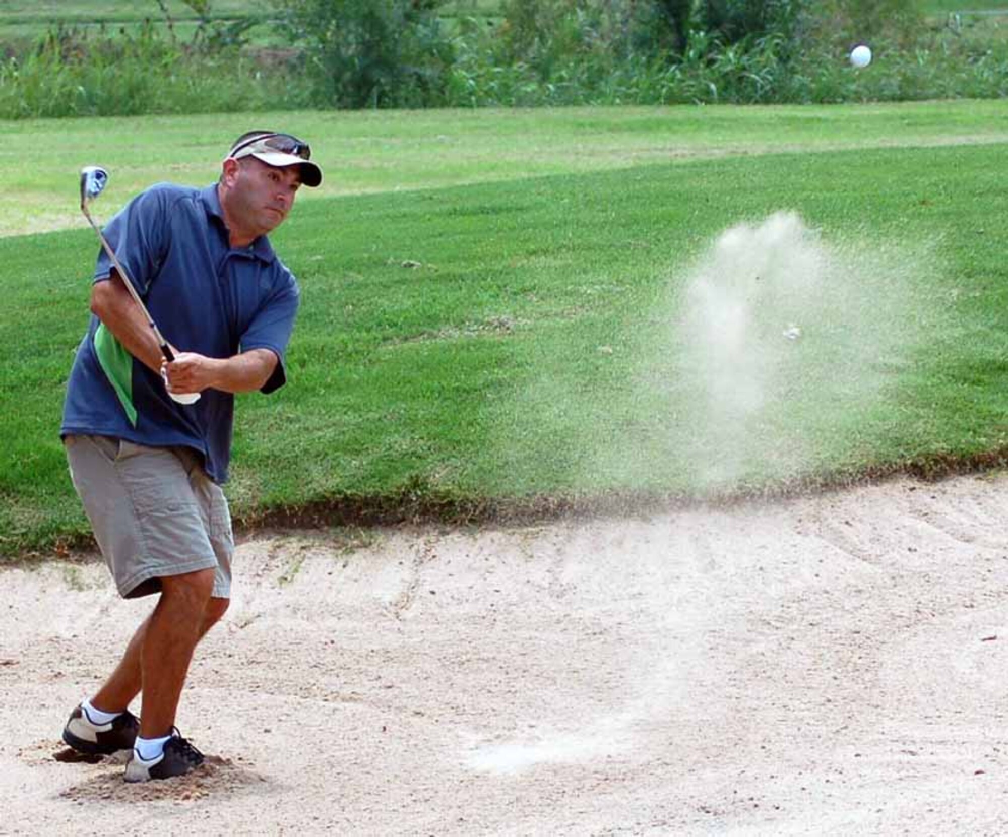 552nd Operational Support Squadron golfer Rick Villarreal chips a bunker shot during the back nine of the small squadron golf championship held Aug. 2 at the Tinker Golf Course. (Air Force photo by John E. Banks)