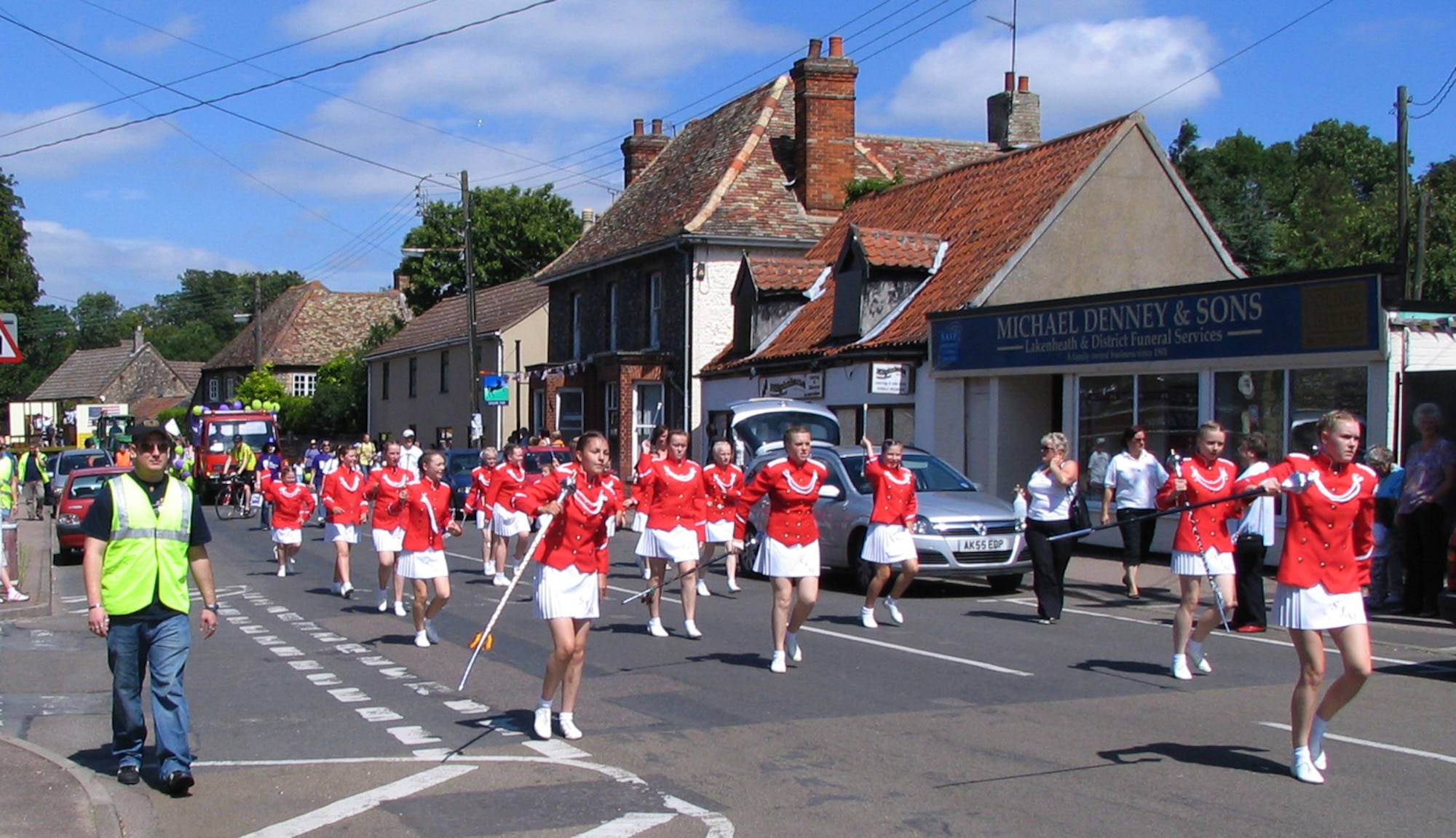 Senior Airman Aaron Schrader, 48th Aircraft Maintenance Squadron, acts as a parade marshal and escorts the Soham Majorettes during the Lakenheath Village festival, August 4. Several Airmen from RAF Lakenheath volunteered as parade marshals for the first Lakenheath Festival. Organizers plan to make this an annual event. (U.S. Air Force photo by Tech. Sgt. J. LaVoie)