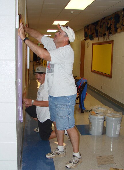Master Sgt. John Steurer,foreground, NCO in charge of airfield systems maintenance, and Don Blose, quality assurance specialist, repair a corkboard in the Eisenhower Elementary School lobby for use as Eisenhower's "Hero" board for pictures of students parents who are deployed.The two were among more than 20 71st Communications Squadron members who pitched in Aug. 3 to spruce up the school in preapartion for the upcoming school year. They painted hallways, bathrooms and a few classrooms; fixed/painted backstop for baseball diamond. (US Air Force photo/2nd Lt James Justice     