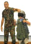 Staff Sgt. Nicholas Jenkins from the 149th Fighter Wing instructs Trey Soule, son of Lt. Col. Laura Soule, 37th Security Forces Squadron commander at Lackland Air Force Base, Texas, on how a gravity suit helps counteract the effects of G-forces during certain flying maneuvers. The demonstration was among several activities Starbase Kelly participants experienced during a weeklong summer camp that ended Aug. 3. (USAF photo by Sid Luna)                               