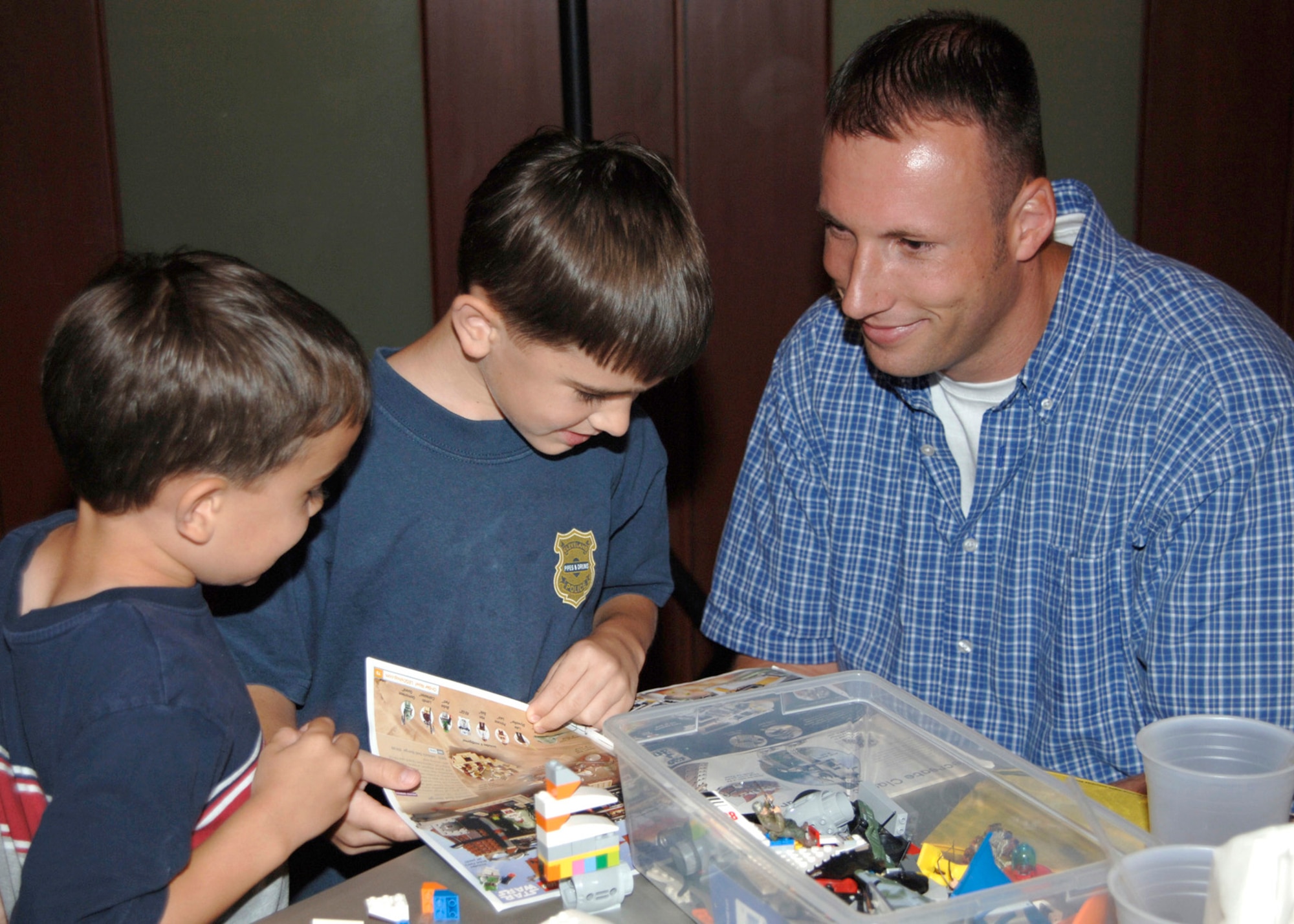 MCCONNELL AIR FORCE BASE, Kan. -- Mike Walling, 931st Operations Support Flight, and sons Anthony, 6, and Michael, 5, play with building blocks during the Lego workshop at Robert J. Dole Community Center, Aug. 2. The workshop helps members share ideas for the upcoming Create a Masterpiece Contest.  (Photo by Amn Justin Shelton)