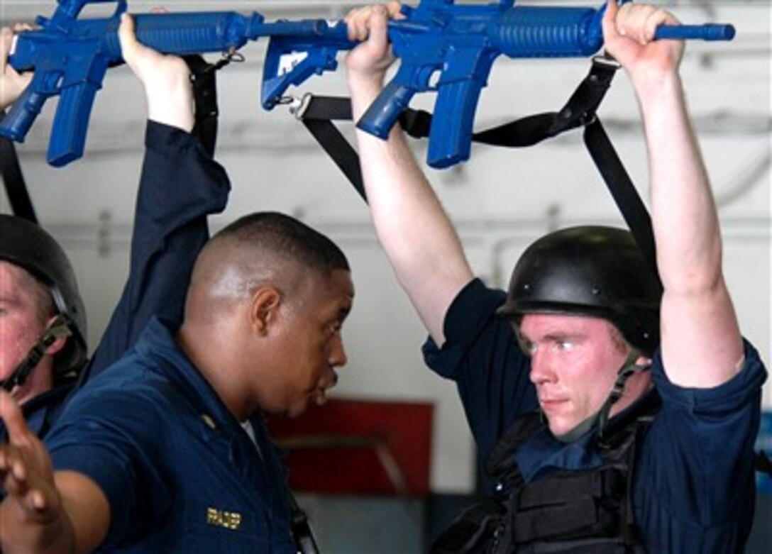 U.S. Navy anti-terrorism instructor Chief Petty Officer Tyjuan Frazier instructs Airman Charles Moran in USS Kitty Hawk's hangar bay, Aug. 8, 2007.