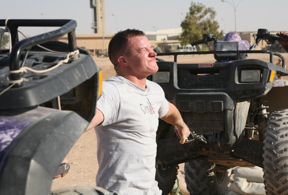 Sgt. Lester Peterson with 1st Battalion, 12th Marine Regiment, Task Force Military Police, reaches deep down inside for everything he has to hold two ATVs during the Hercules Hold event of the Al Asad Strongman Competition, Aug. 12. Competitors were split up into various weight classes and competed in events like the Atlas Stone carry and Farmer?s Walk.