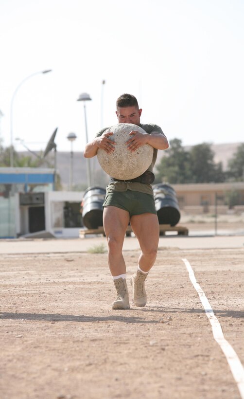 Cpl. Chris Spinazzola with 1st Battalion, 12th Marine Regiment, Task Force Military Police, keeps a tight grip on the stone and his legs moving during the Atlas Stone Carry event of the Al Asad Strongman Competition, Aug. 12. Unlike the Atlas Stones event in the Worlds Strongest Man competition where competitors have to put five different stones on pedestals, competitors in the Al Asad Strongman Competition had to carry the stone as far as they could.